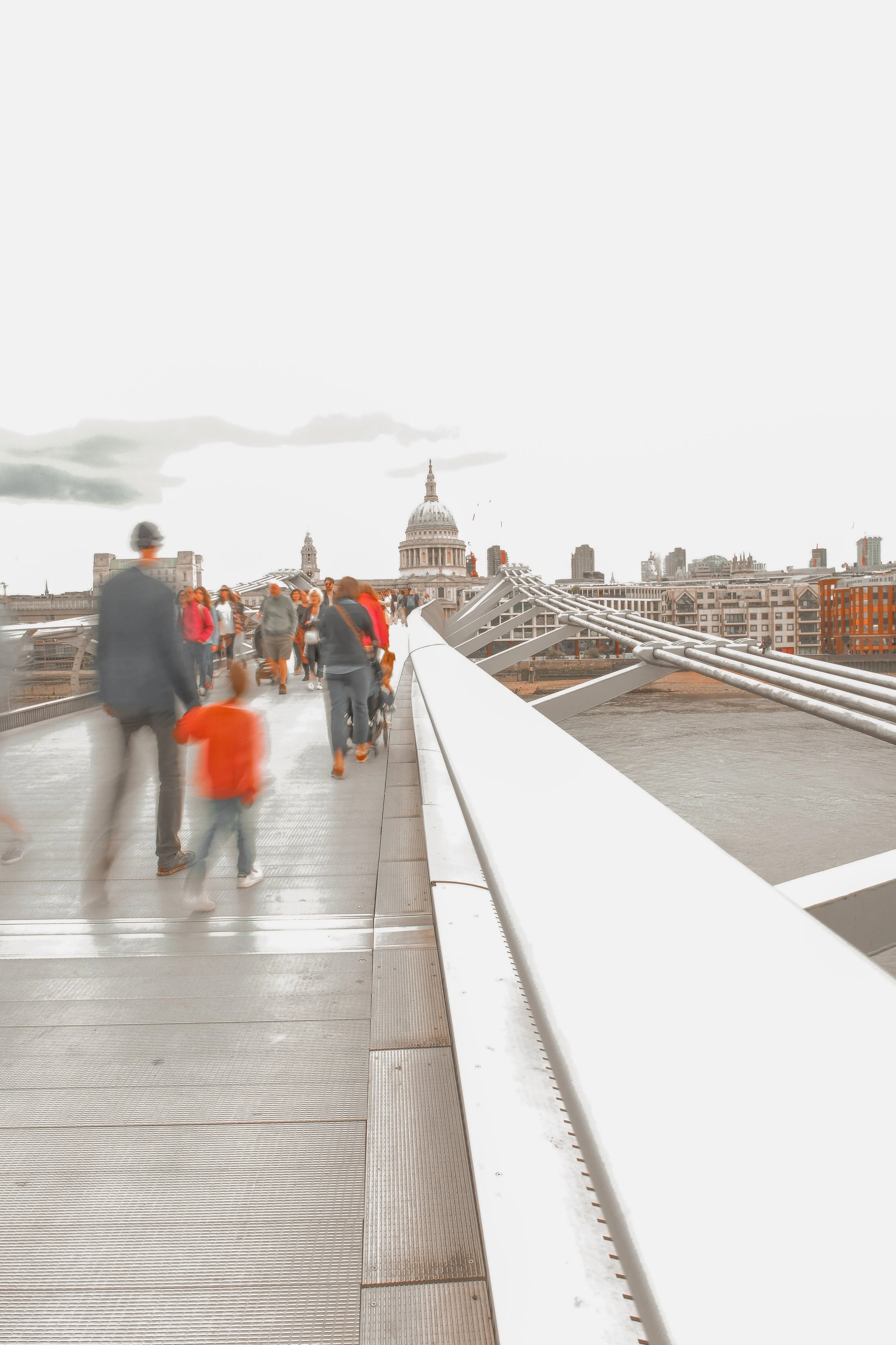 People walking on the Millennium Bridge with St. Paul's Cathedral in the background in London, England.