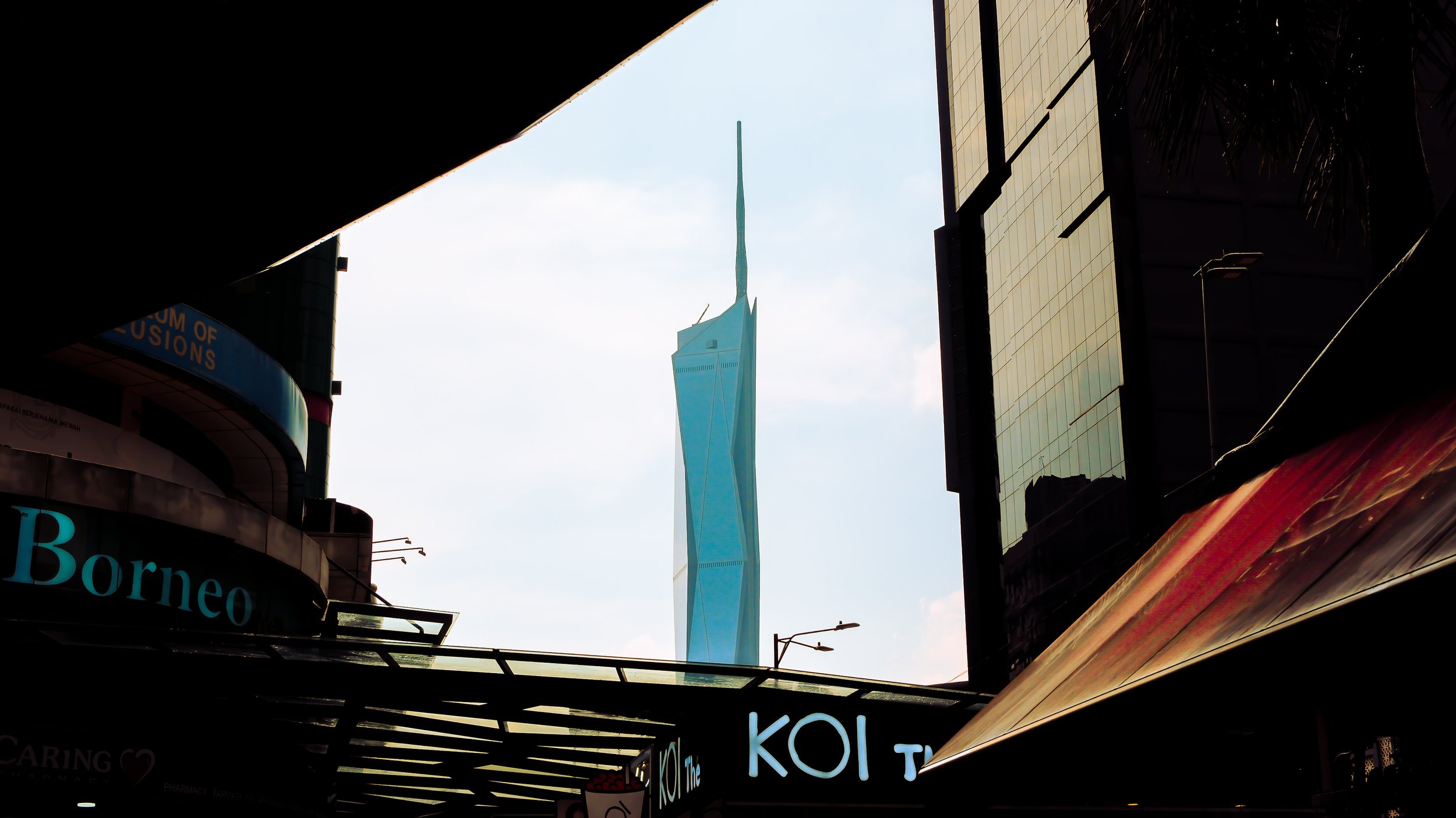 View of the Stratosphere Tower in Las Vegas framed between buildings and signs in a city setting.