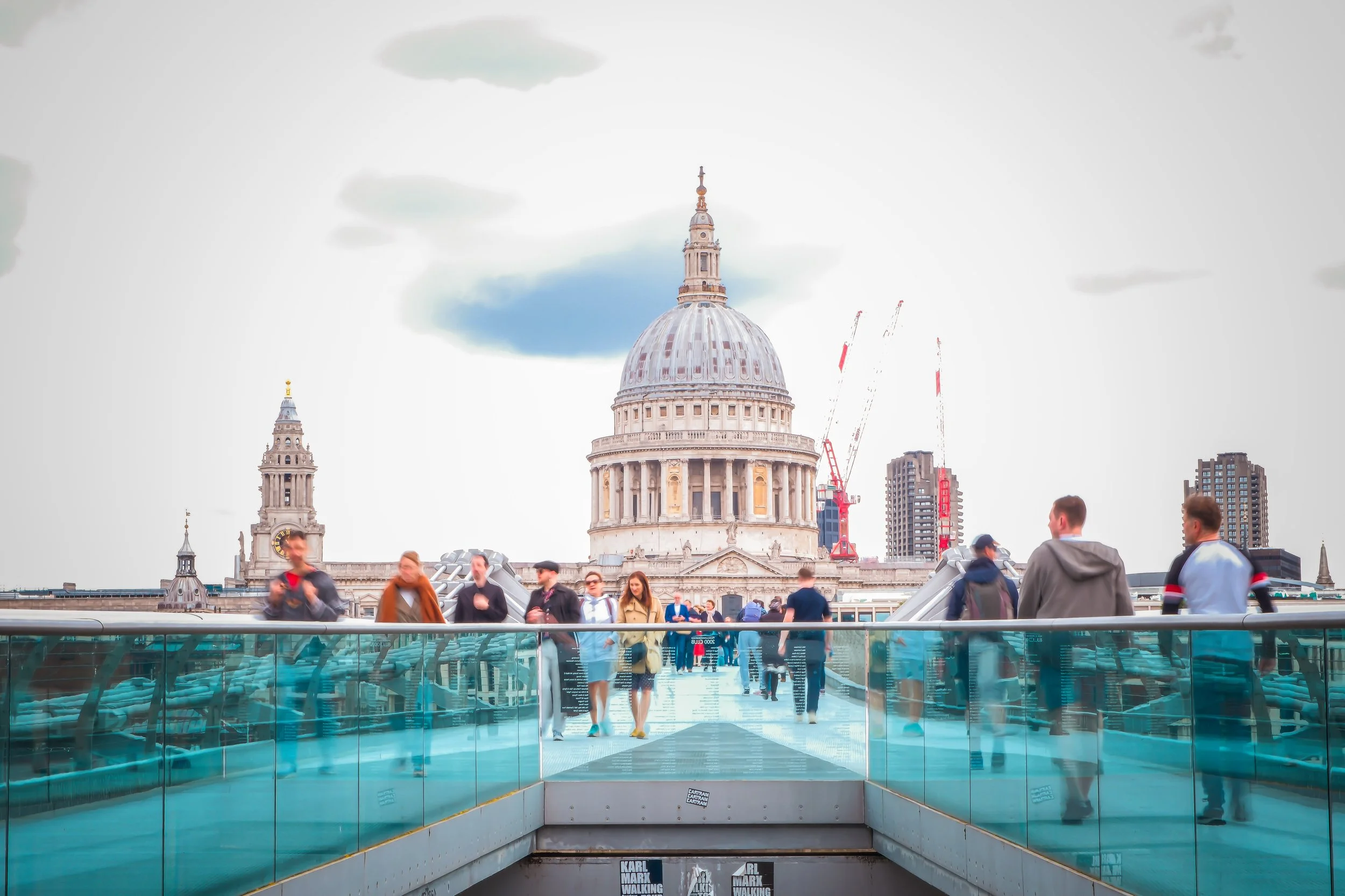 Tourists and visitors on the Millennium Bridge with St. Paul's Cathedral in London in the background.