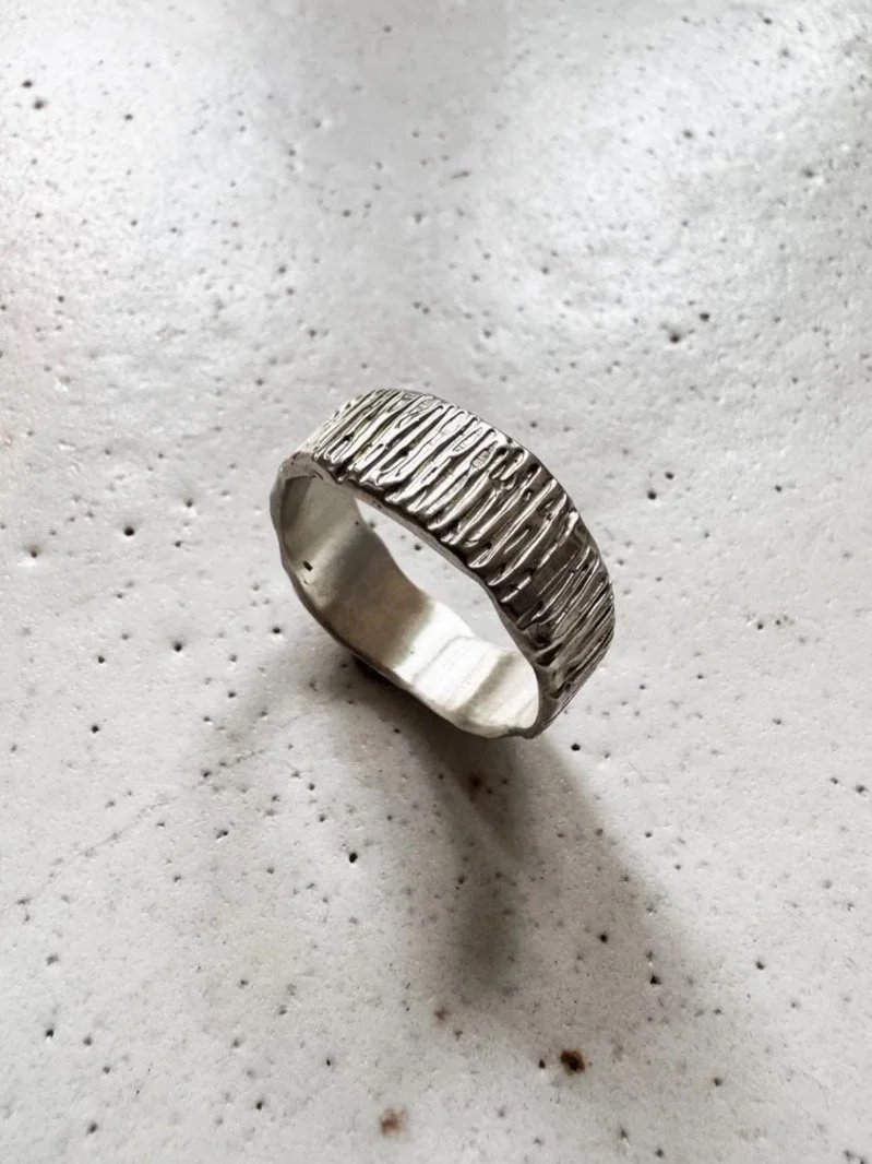 Handcrafted men’s sterling silver ring with a wide band, organic edges and textured surface, made from 100% recycled 925 silver.