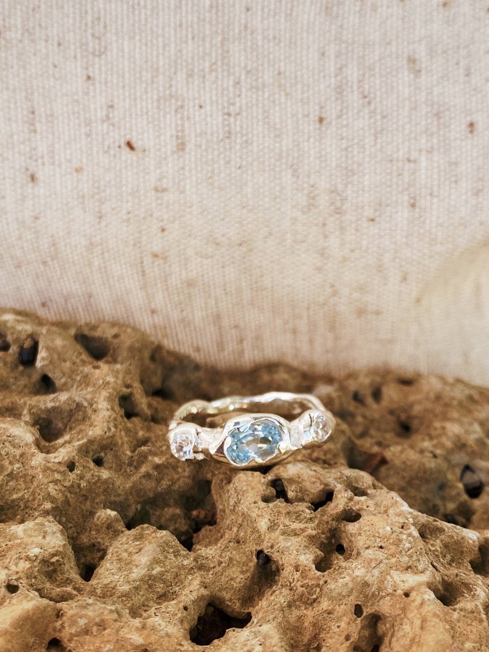 Wabi-sabi gemstone ring with a natural light blue topaz and diamond accents, crafted by hand in recycled precious metals.