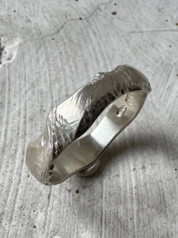 Wide sterling silver band ring with a rugged engraved texture and asymmetrical shape for a bold masculine look.