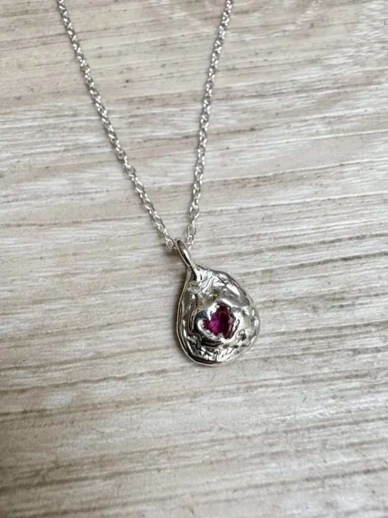 Handmade ruby necklace in recycled 925 sterling silver with a deep red gemstone, organic pendant shape and raw wabi-sabi texture.