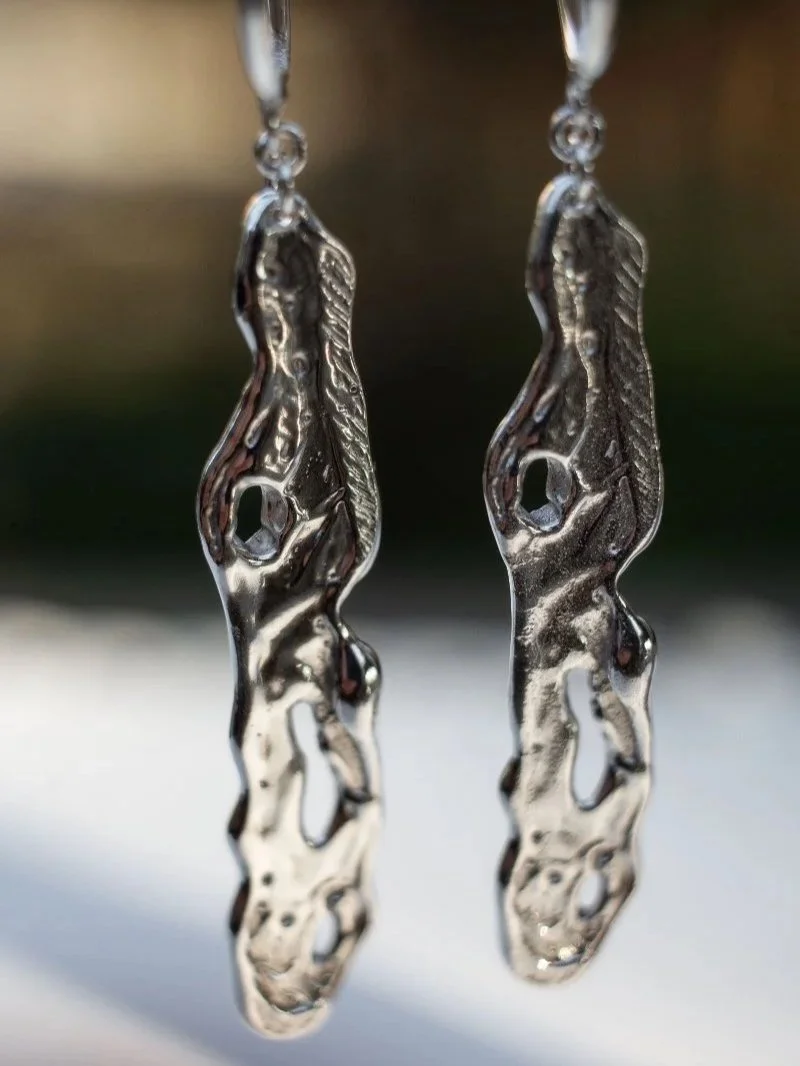 Modern sculptural silver earrings with organic liquid texture, handmade from recycled silver.