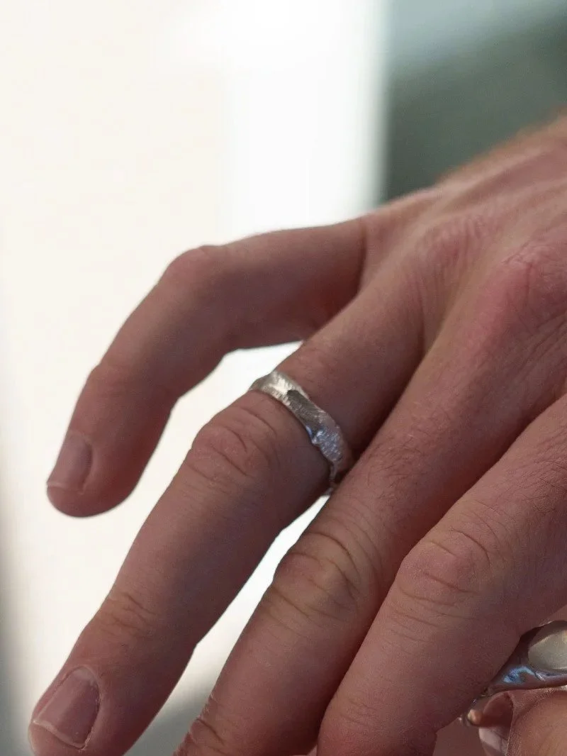 Modern men’s wedding band in sterling silver with raw organic edges and a bold handcrafted textured finish.
