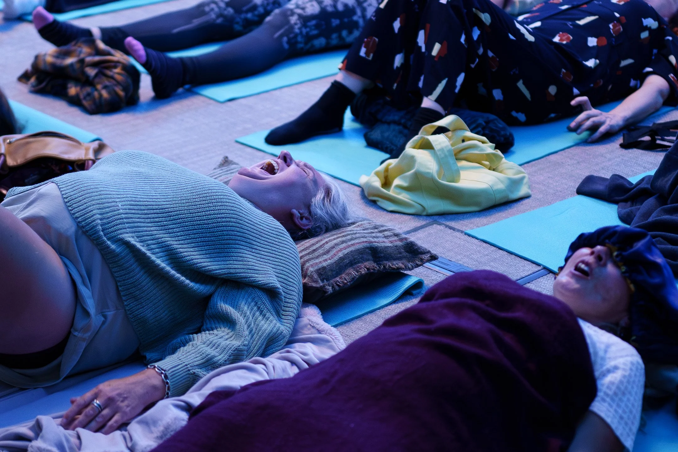People practicing breathwork for emotional release on mats outdoors during twilight, lying down and screaming.