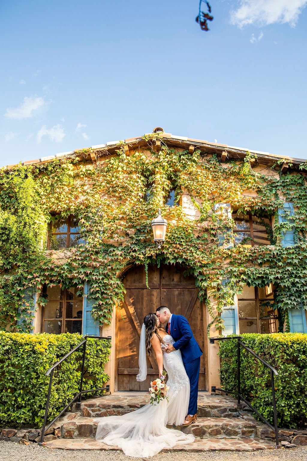 A couple kissing in front of the Crush House after getting married at Milagro in Ramona, California.