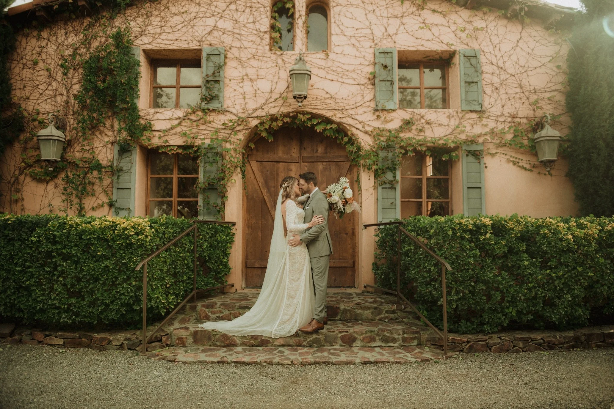 A couple kissing in front of the Crush House after getting married at Milagro in Ramona, California. 