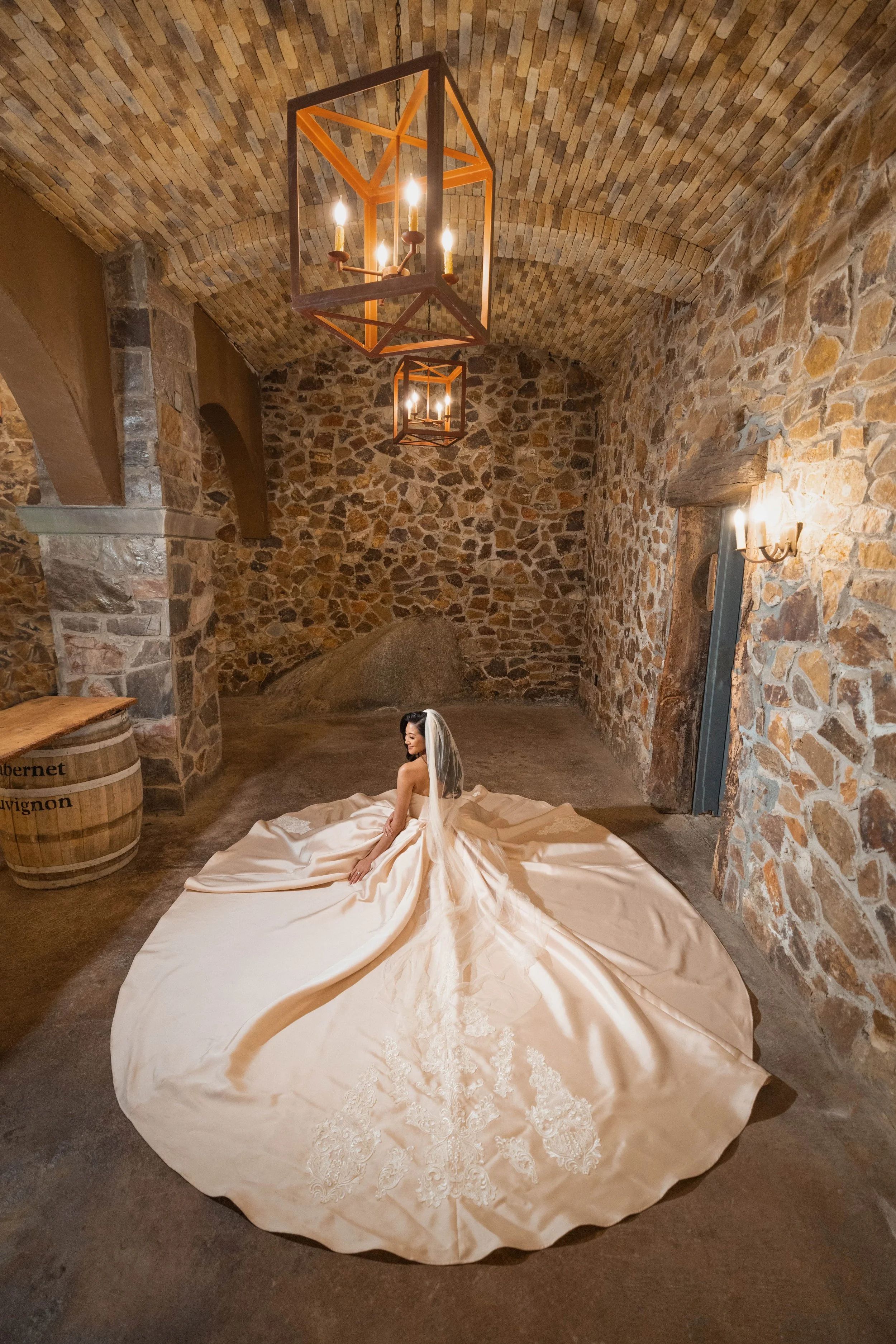 A bride with a long wedding dress standing in the Wine Cave with gorgeous high ceilings and stone walls at Milagro in Ramona, California.