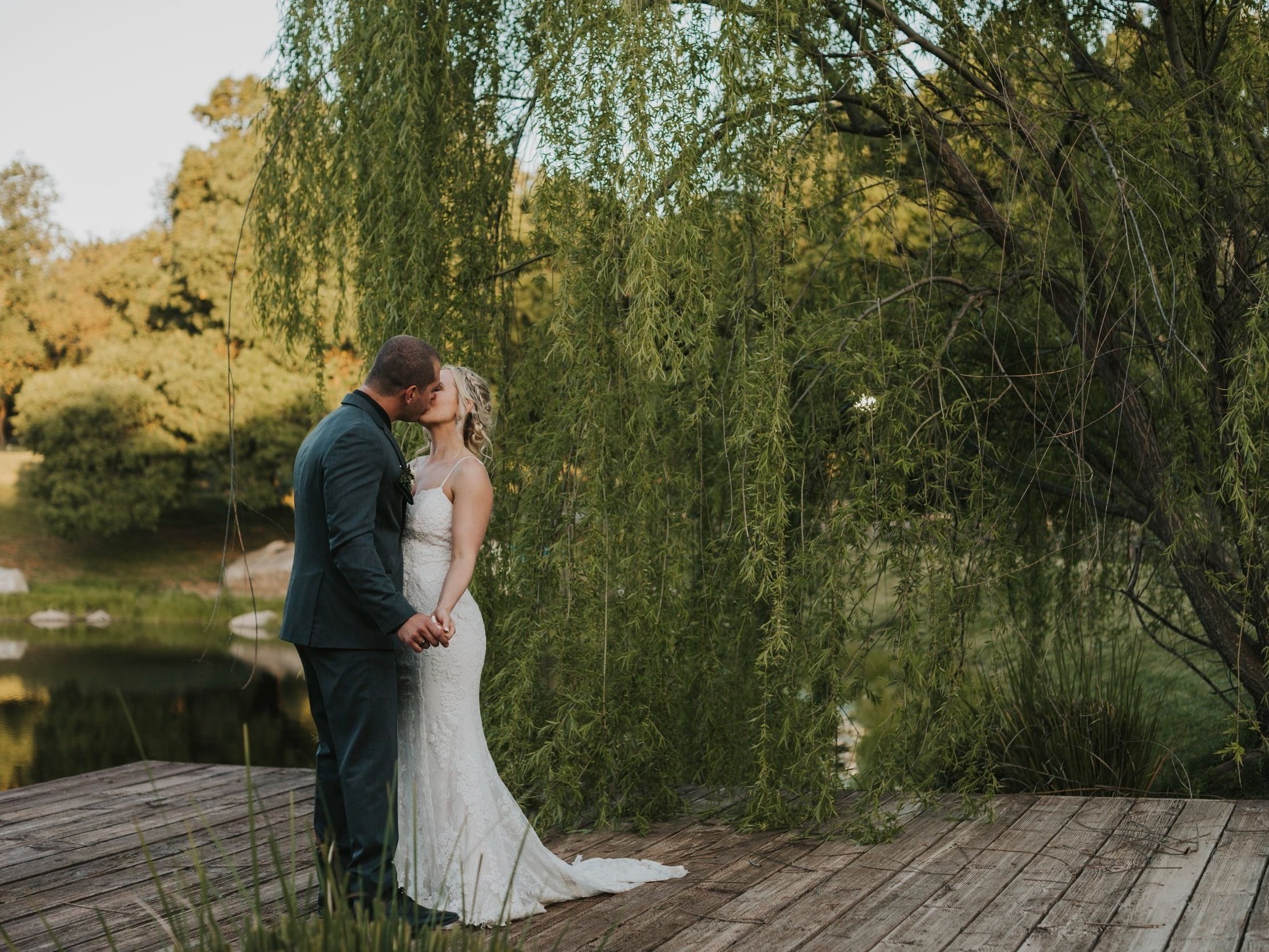 A couple kissing in front of the lake after getting married at Milagro in Ramona, California.