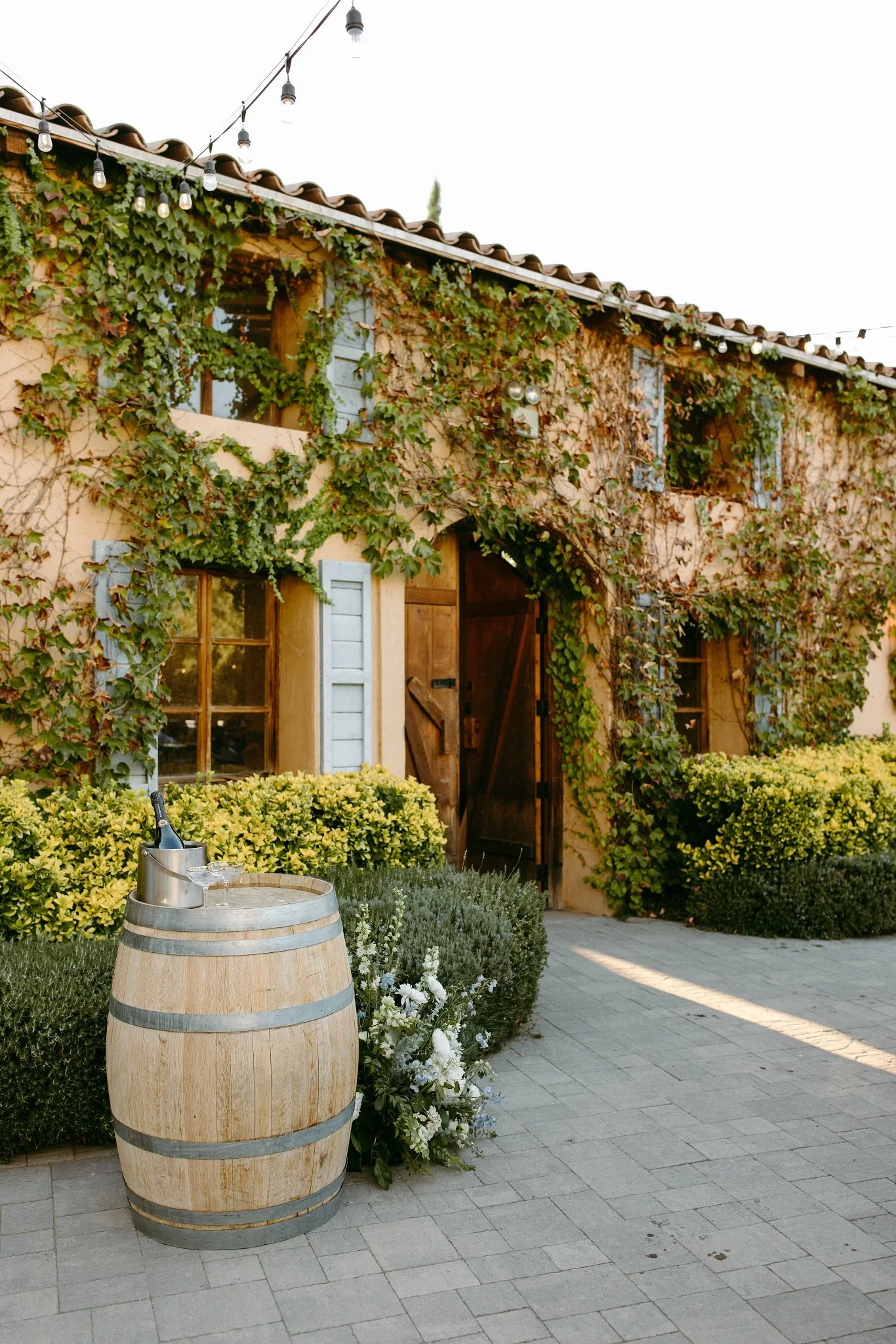 A side view of the romantic entryway to the Crush House with a wine barrel and a bottle of wine at Milagro in Ramona, California.