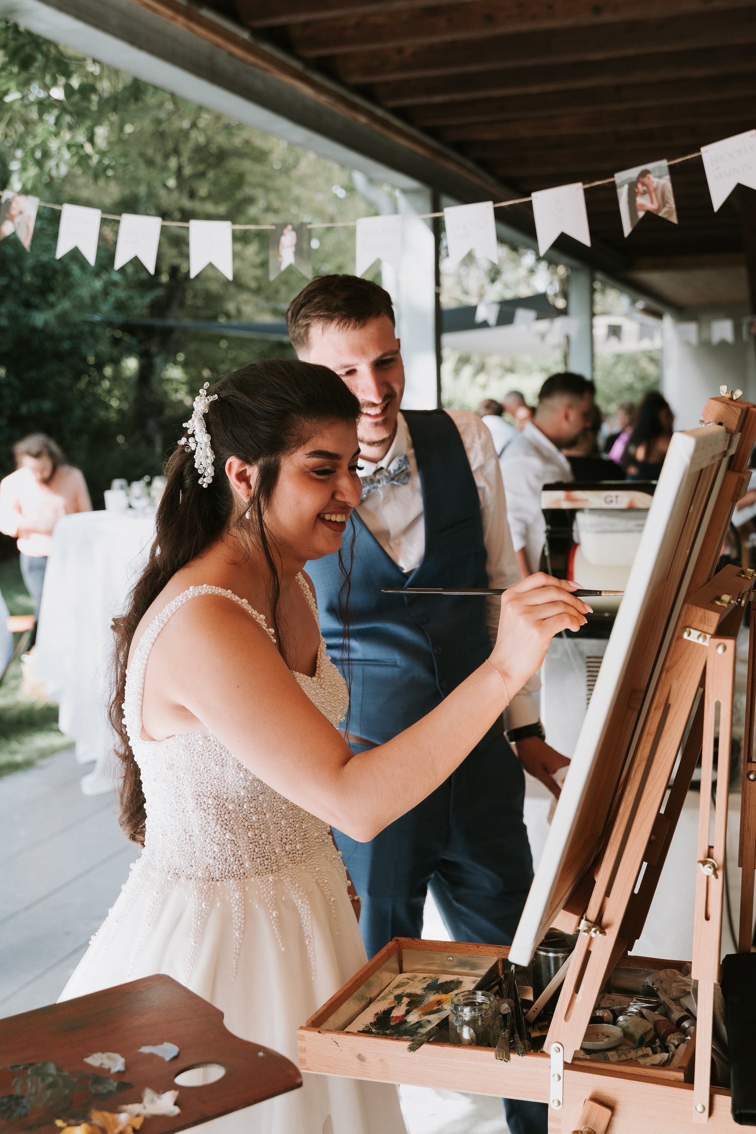 Bride and groom paints their wedding with the help of a live wedding painter. Interactive painting.