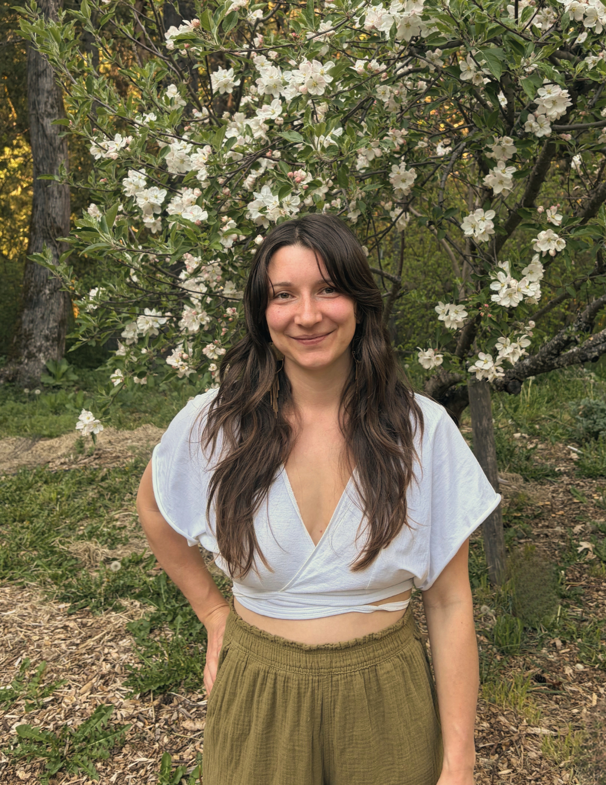 Kelsi Wathen, birth & postpartum doula, happily standing in front of a flowering tree after a postpartum planning session.