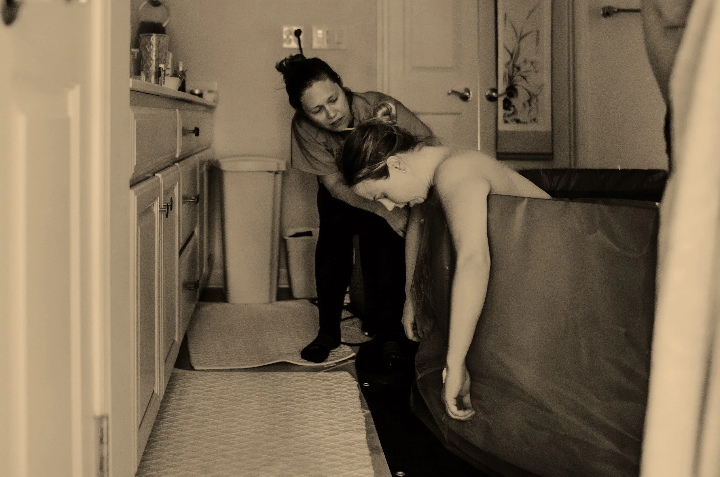 Doula supporting mother through a home birth in a birth pool in Oregon.