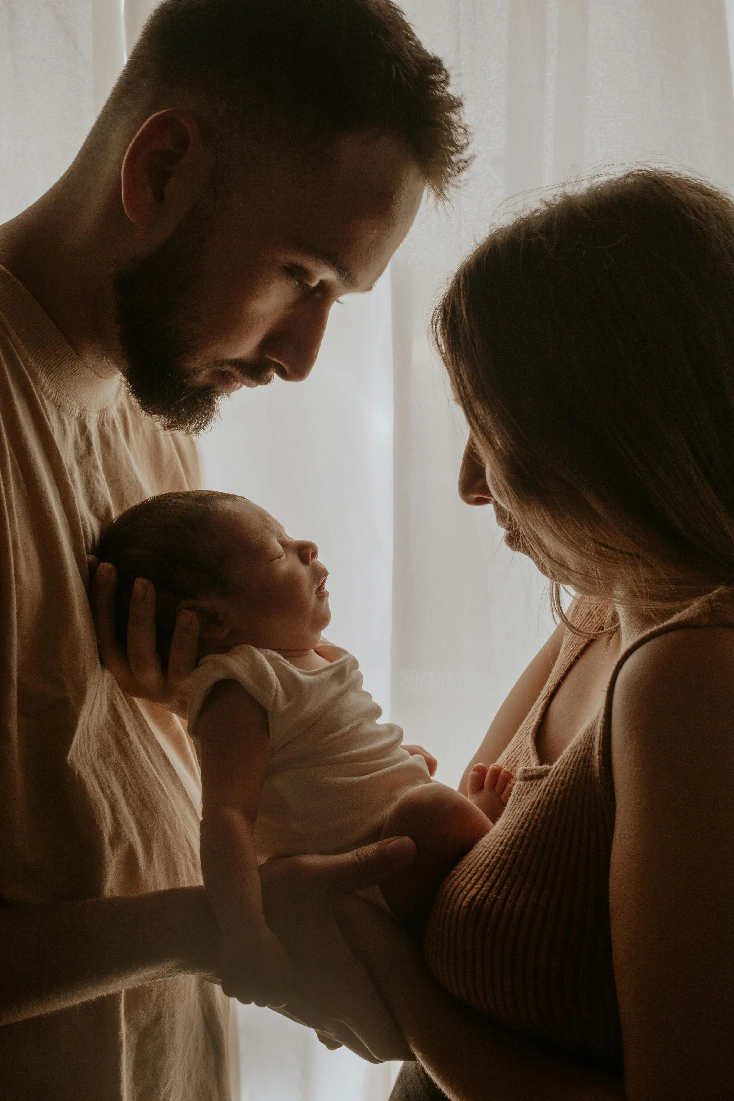 Postpartum mother, father, and baby resting while postpartum doula cooks them a nourishing meal.