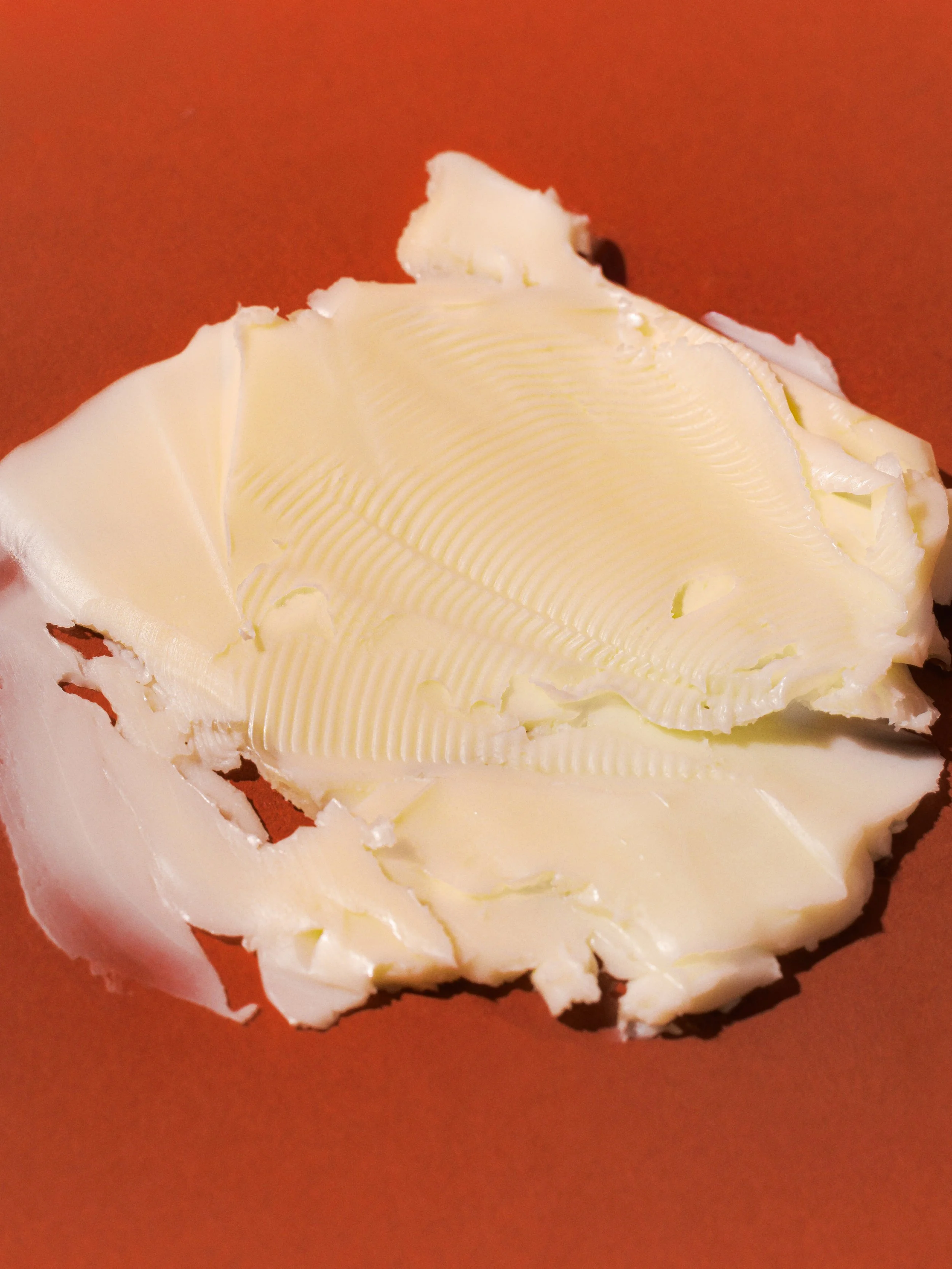 A close-up of a block of butter on a brown surface.