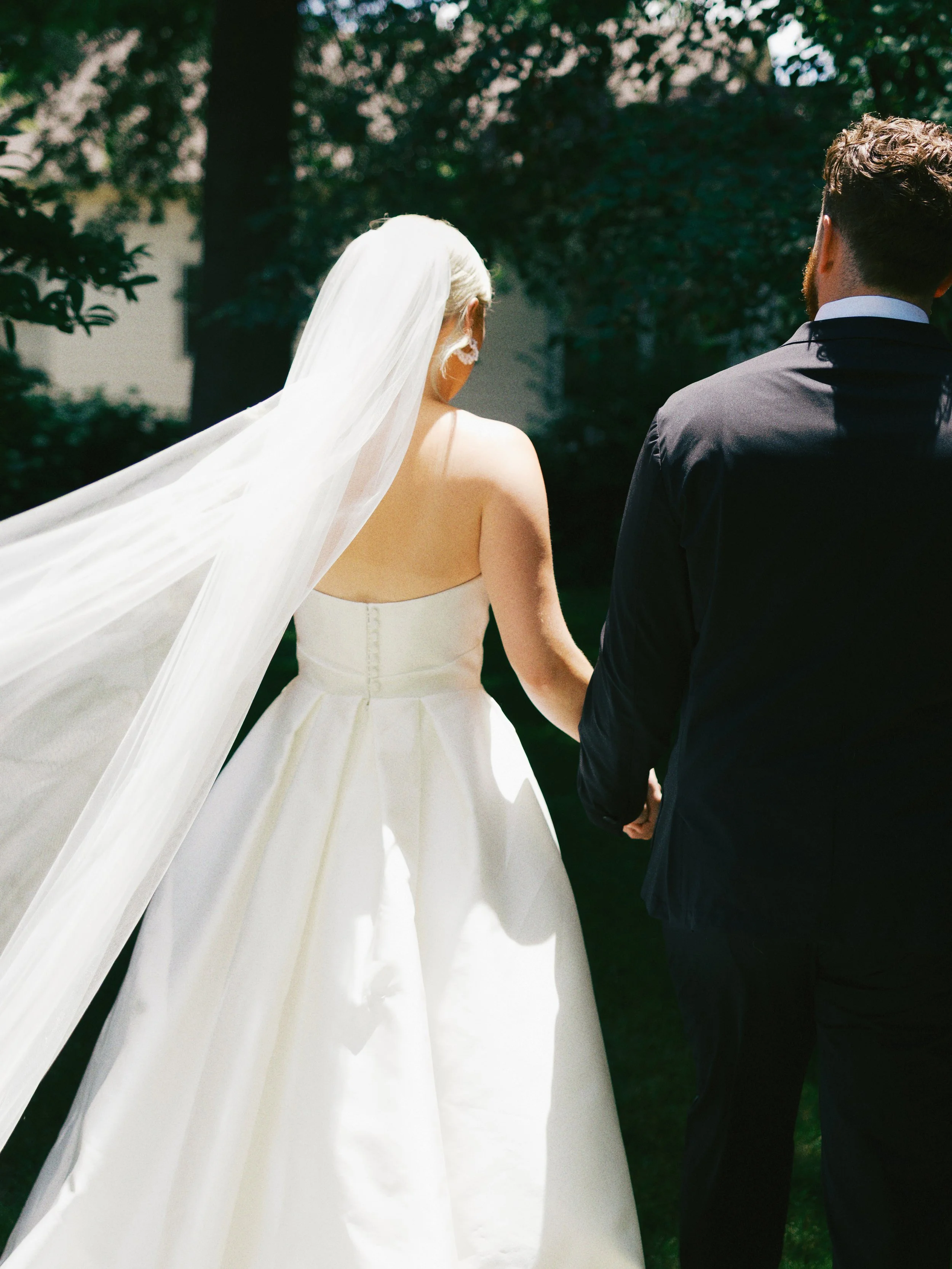 bride with veil in stunning light with groom