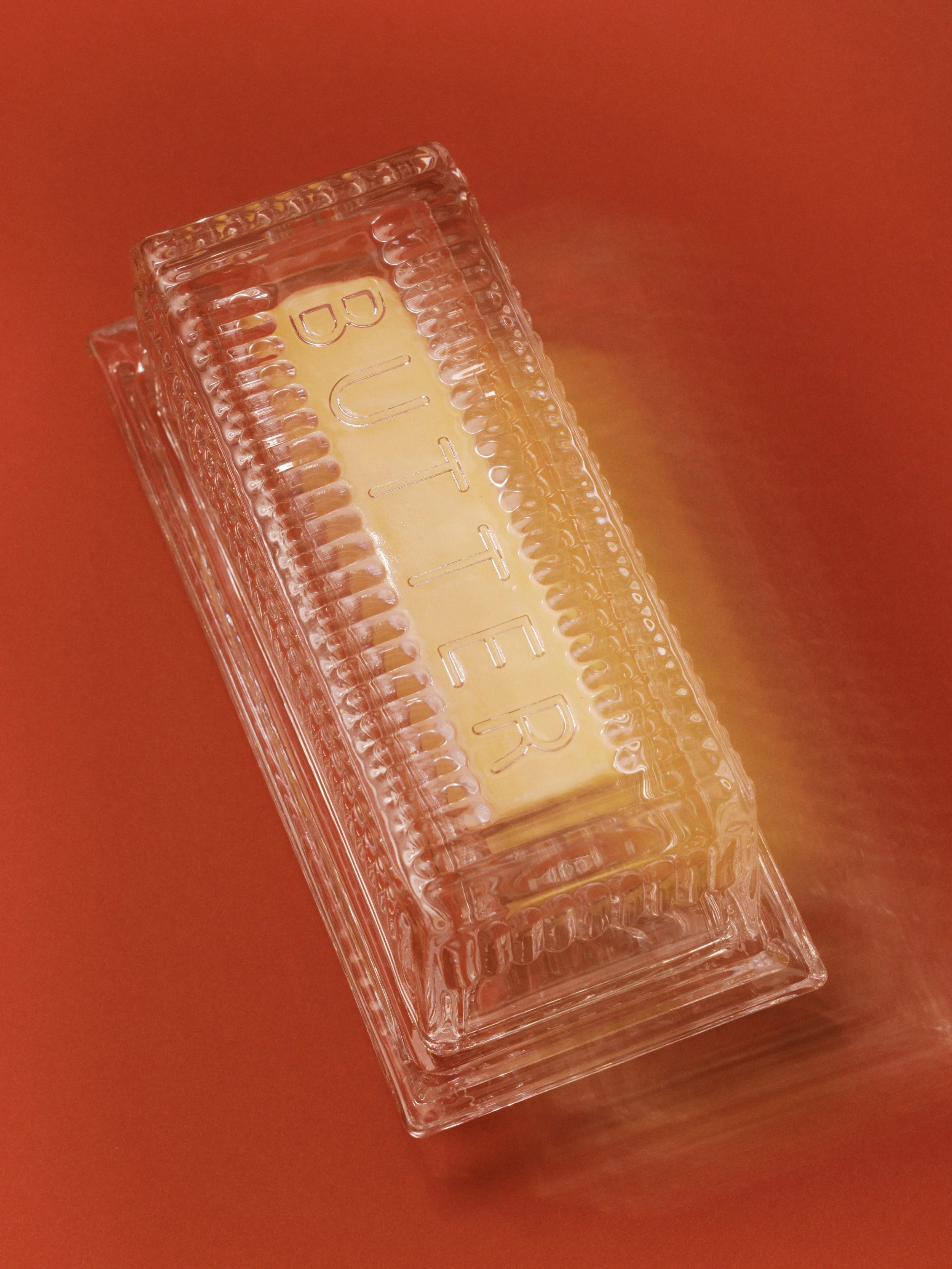 Close-up of a clear glass container with a yellow label reading 'CUT' on a reddish-orange surface.