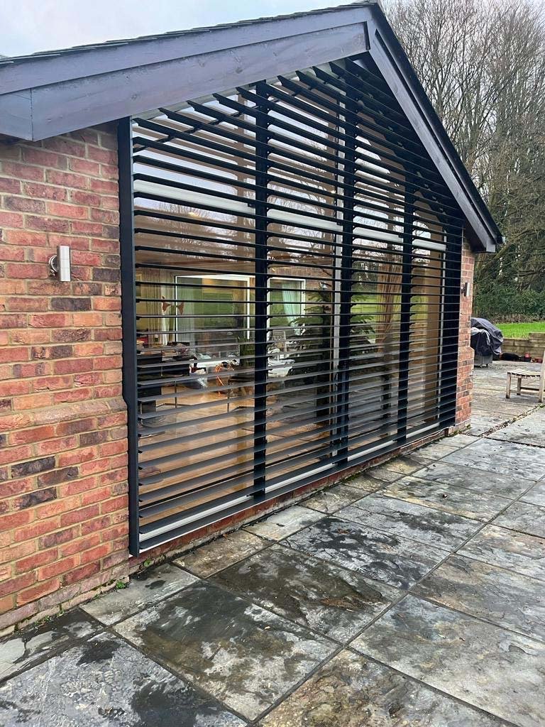 side angle view of exterior louvres fitted to large windows on a beautiful home inWinchester