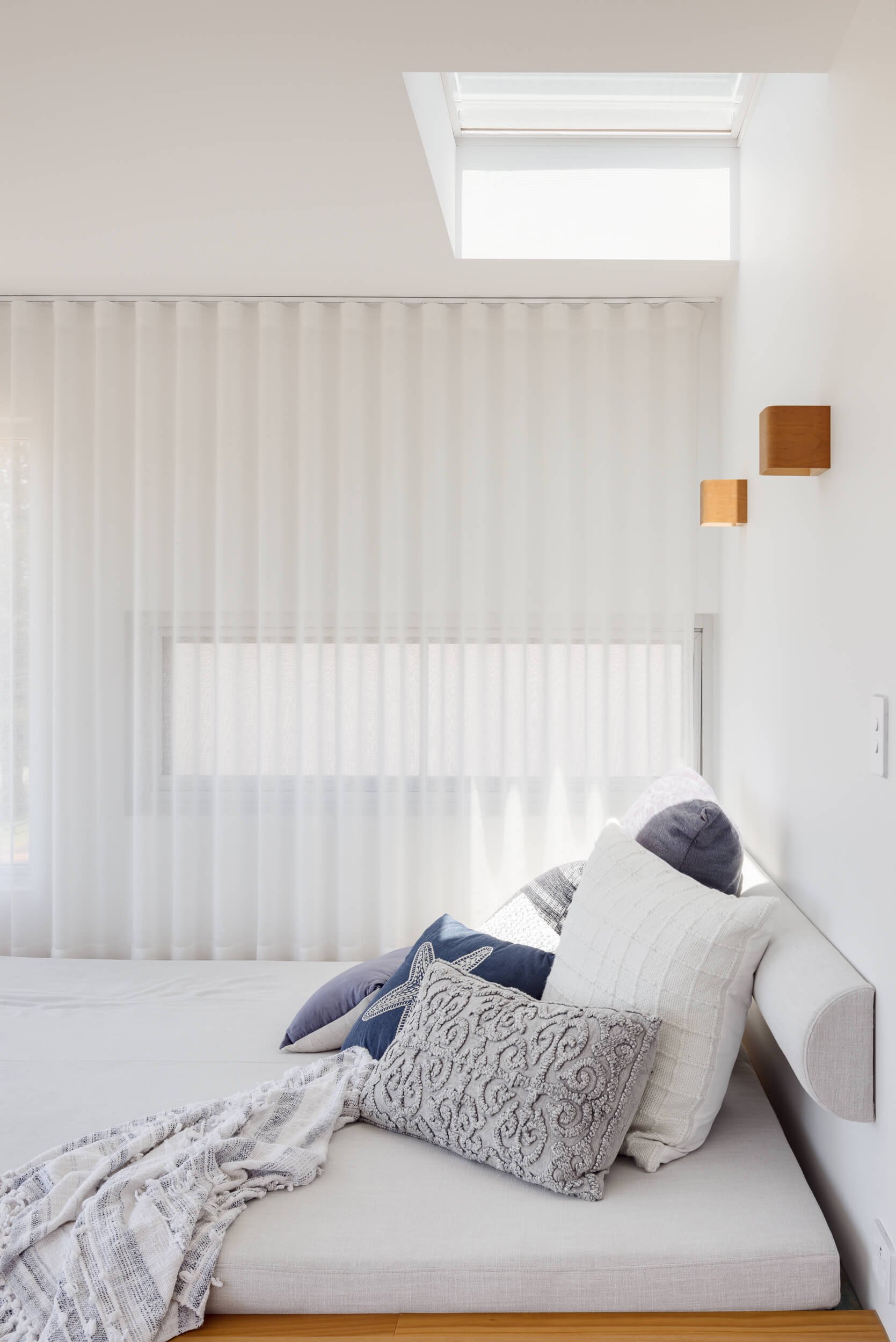 Built-in bedroom daybed with soft furnishings and skylight at Pacific 5. Premium architectural photography and film documenting true materiality and craftsmanship for Master Builders, architects and designers in Regional NSW.