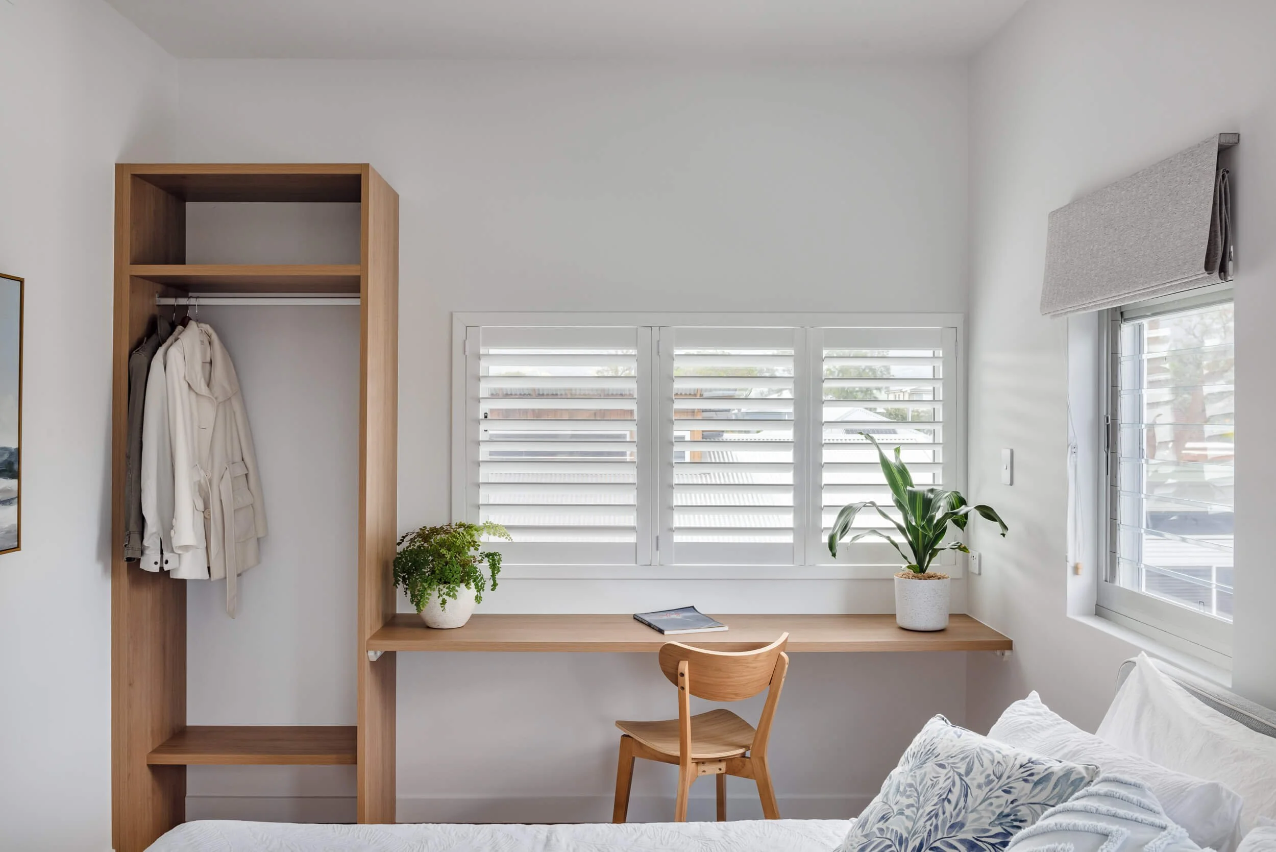 Built in timber desk and wardrobe joinery with plantation shutters in a coastal bedroom at Pacific 5. Premium architectural photography and film documenting true materiality and craftsmanship for Master Builders, architects and designers in Regional