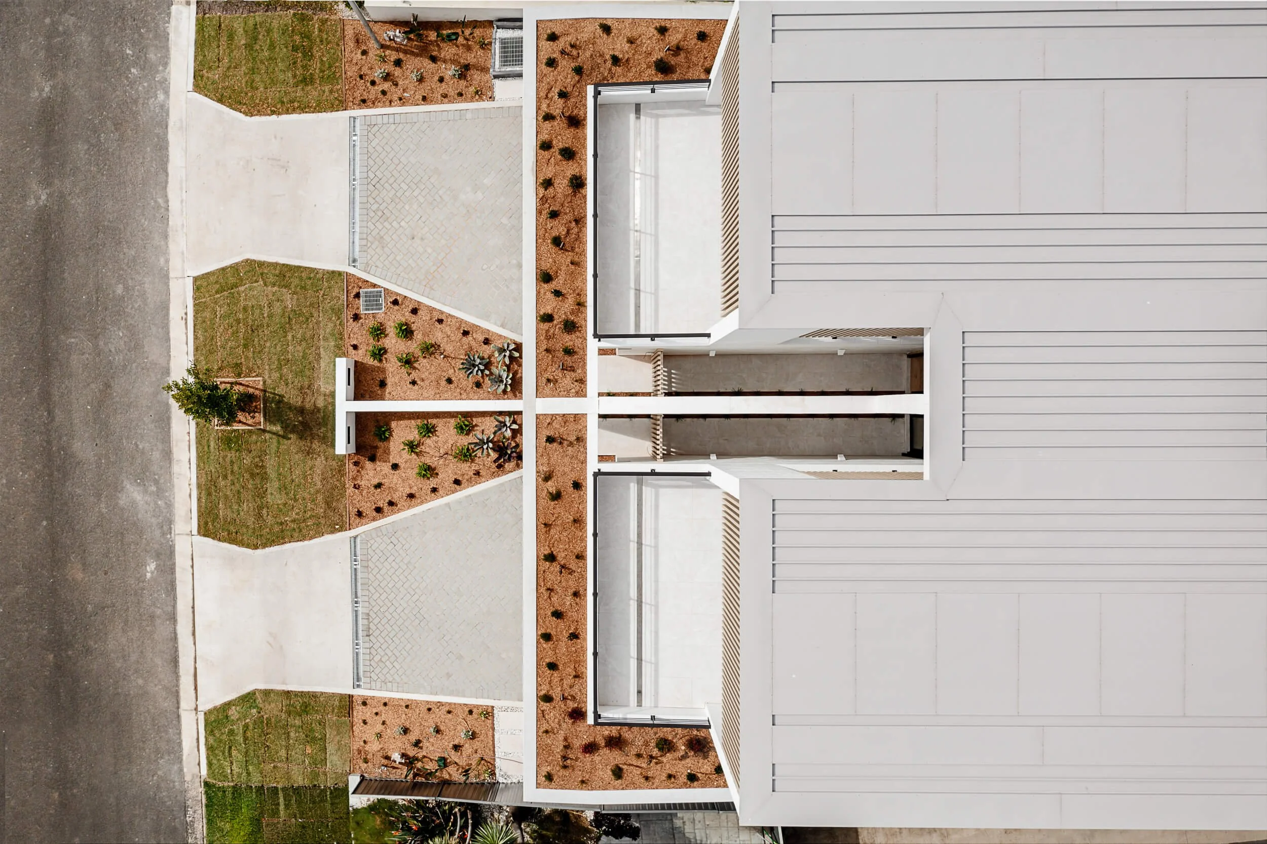 Architectural drone plan view of O'Brien Duplex Bulli highlighting symmetrical driveways, landscaped garden beds, and suspended concrete terrace by Kibbin Design