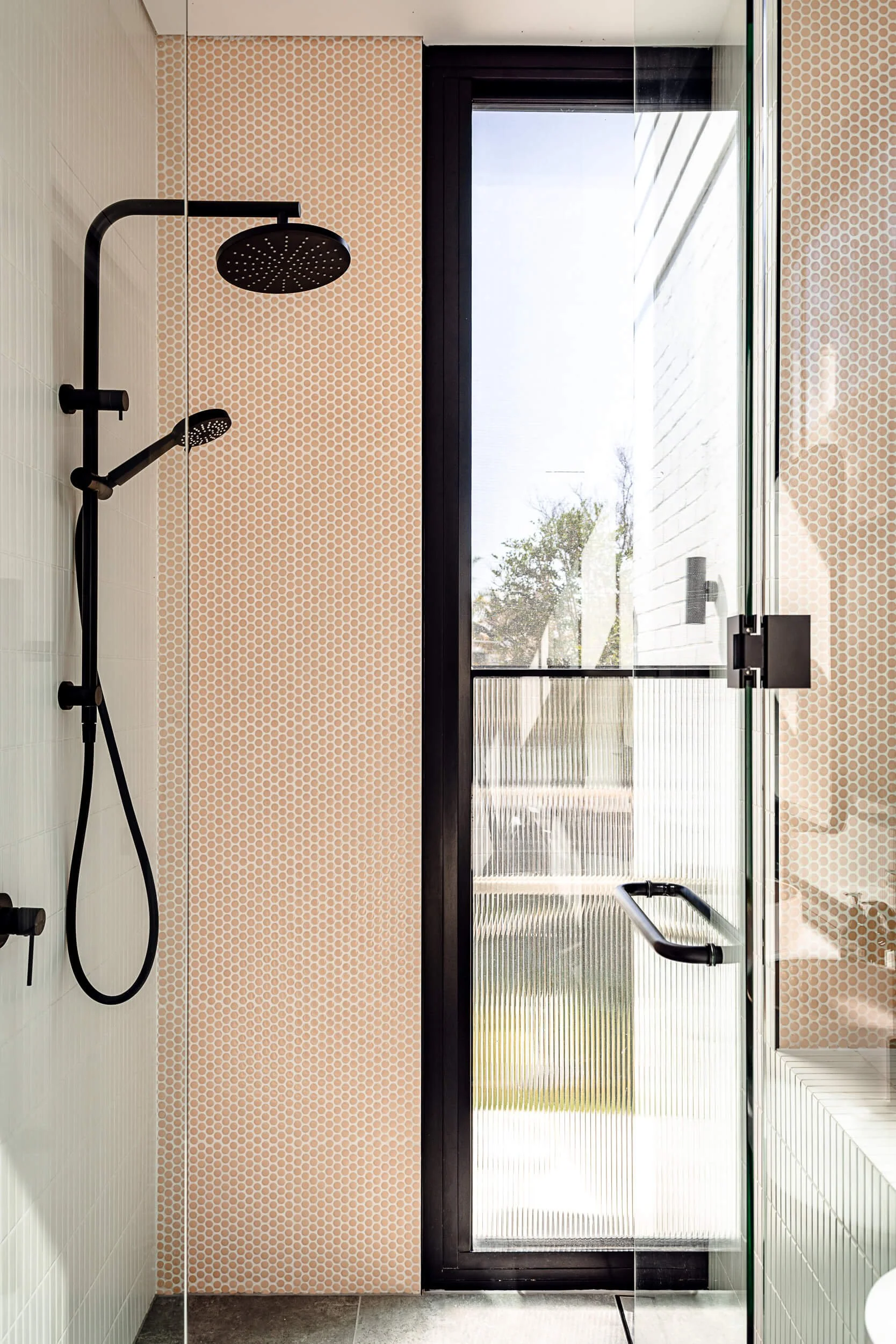 Ensuite shower featuring blush pink penny-round mosaic tiles, matte black shower fittings, and a fluted glass door at Bondi Heights in Sydney, NSW