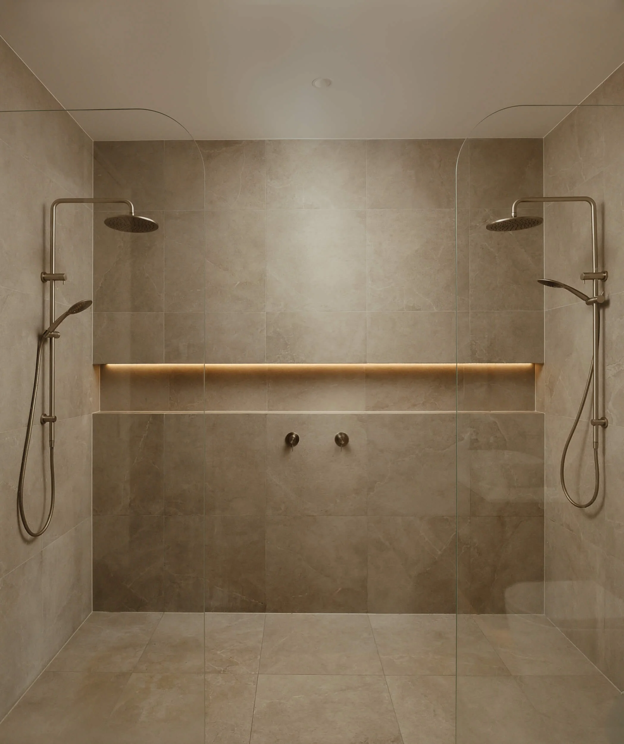 Double walk-in shower featuring large-format stone tiles, integrated LED niche lighting, and twin brushed fixtures at Stonemasons House in Vaucluse, NSW