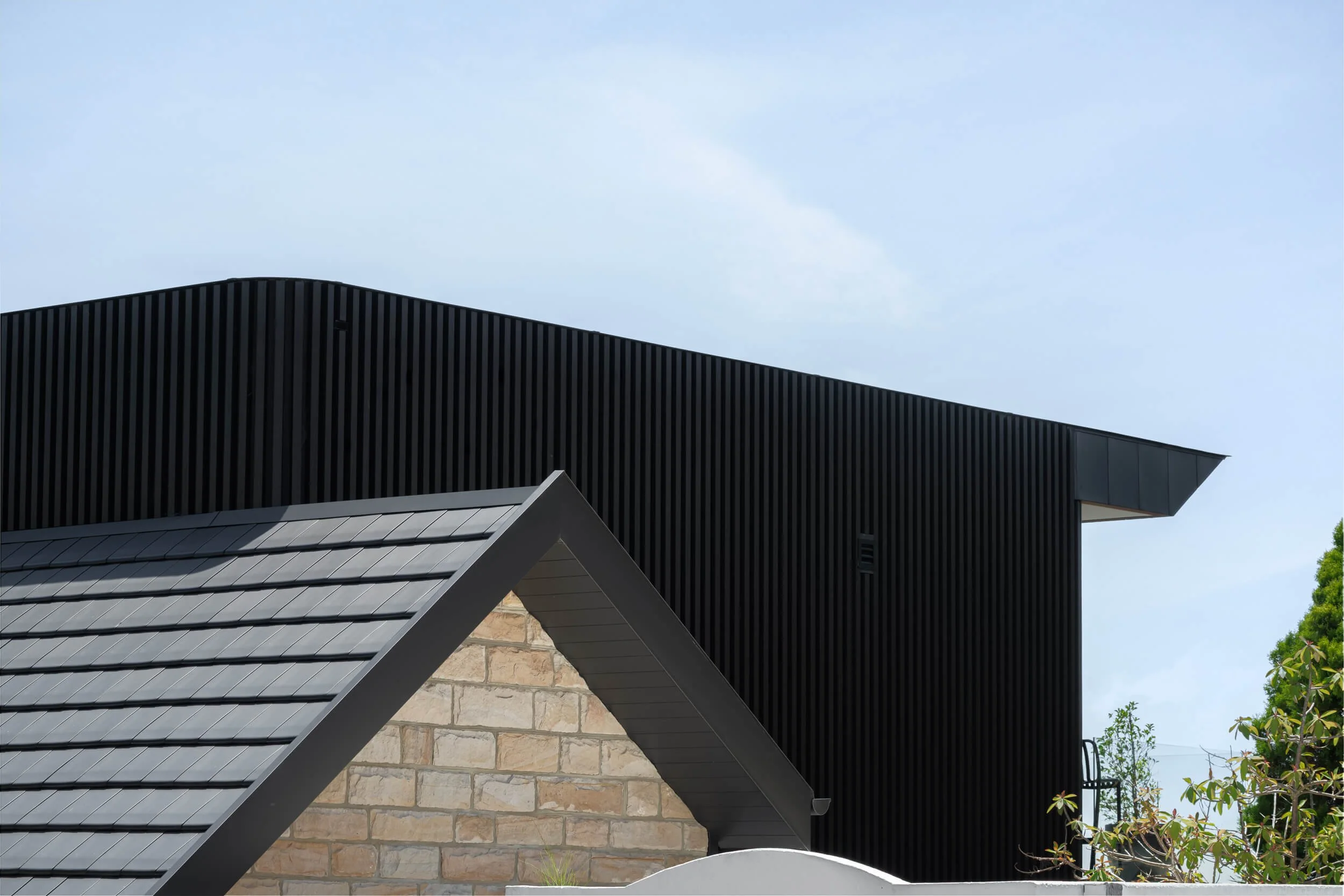 Detail of a dark chamfered roof and black timber cladding interfacing with heritage sandstone.  Premium architectural photography and film documenting true materiality and craftsmanship for Master Builders and architects in regional NSW