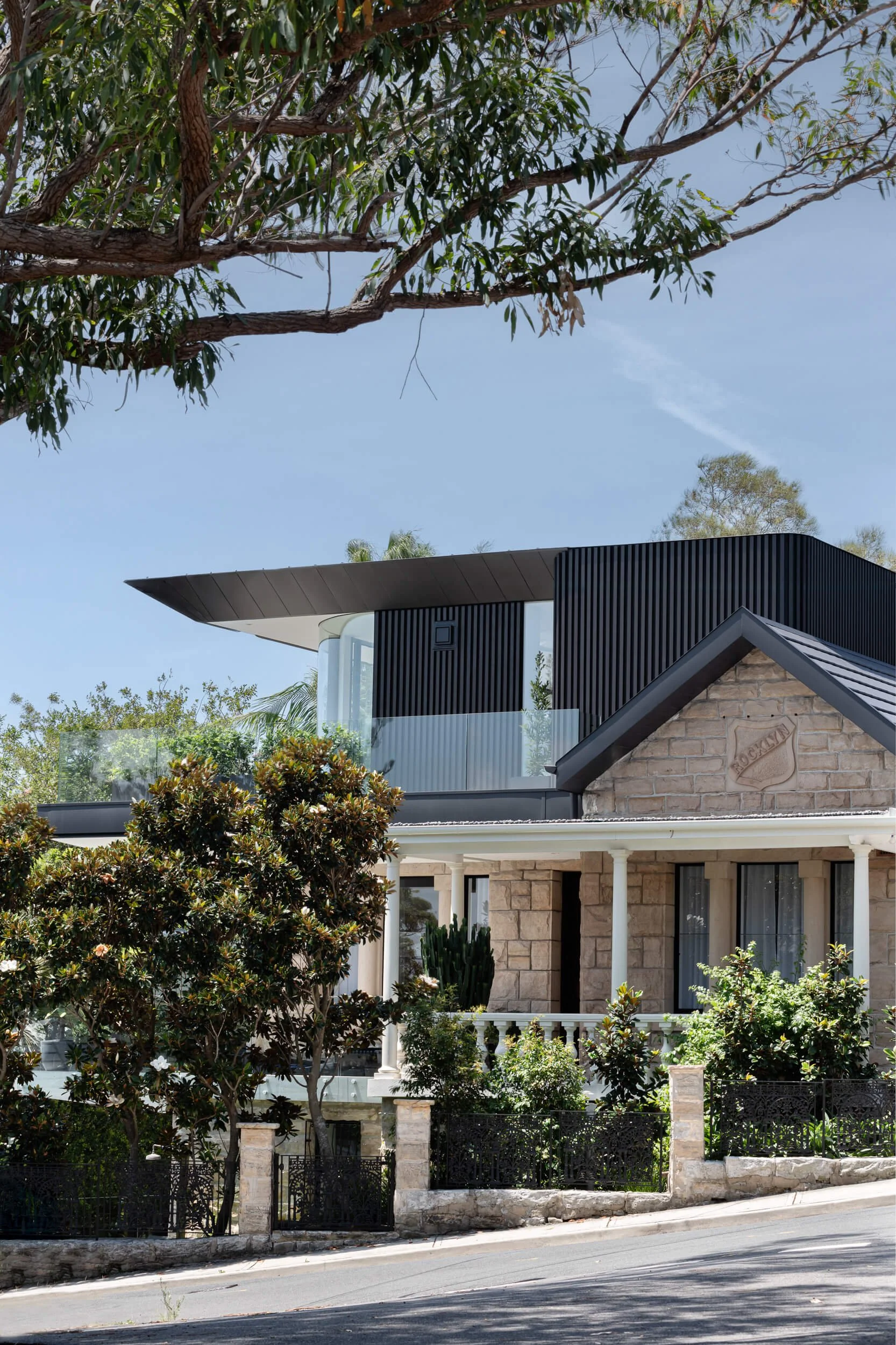 Vertical facade view showing dark gabled extension and foliage at Stonemasons House