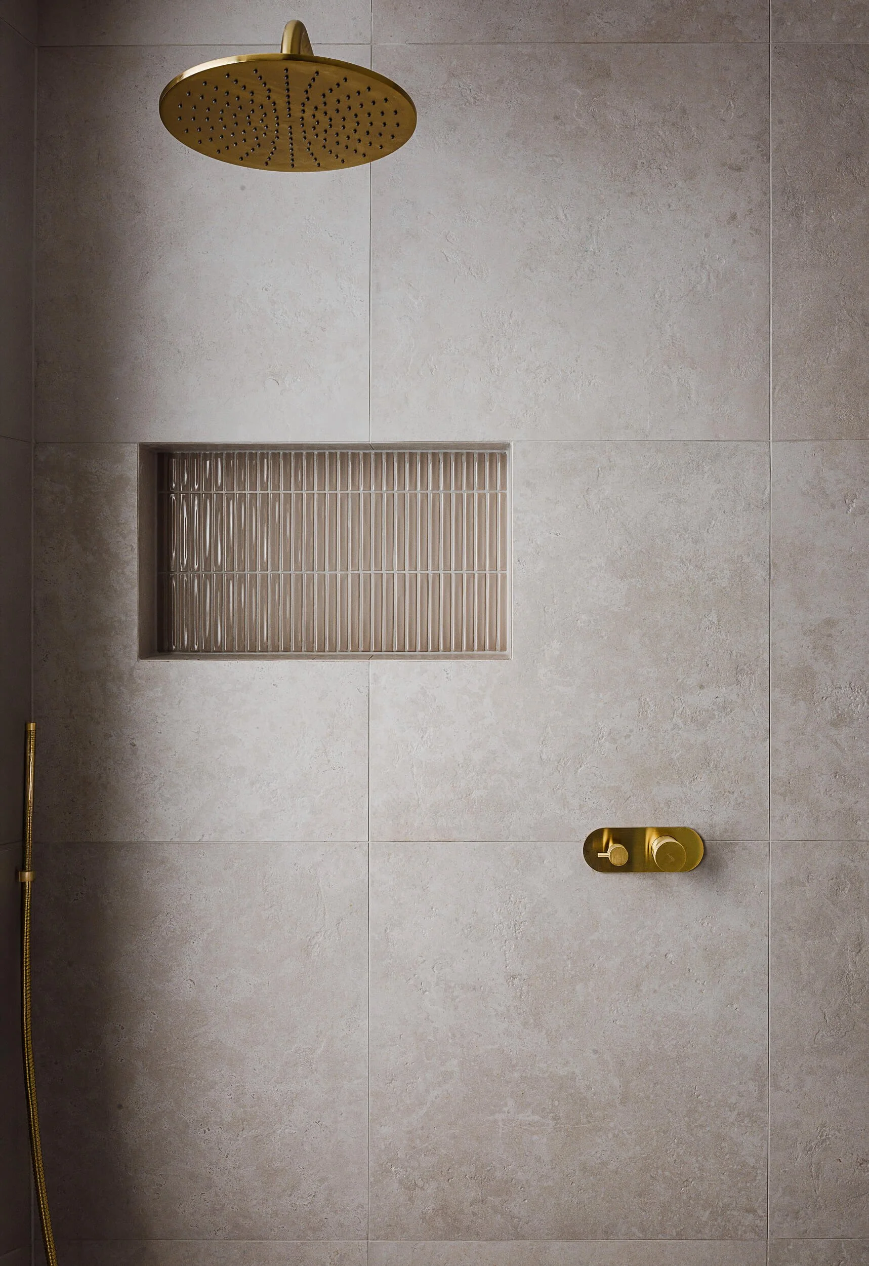 Ensuite shower detail at O'Brien Duplex Bulli featuring brushed brass shower rose, mixer tapware, and recessed vertical fluted tile niche by SLD Projects