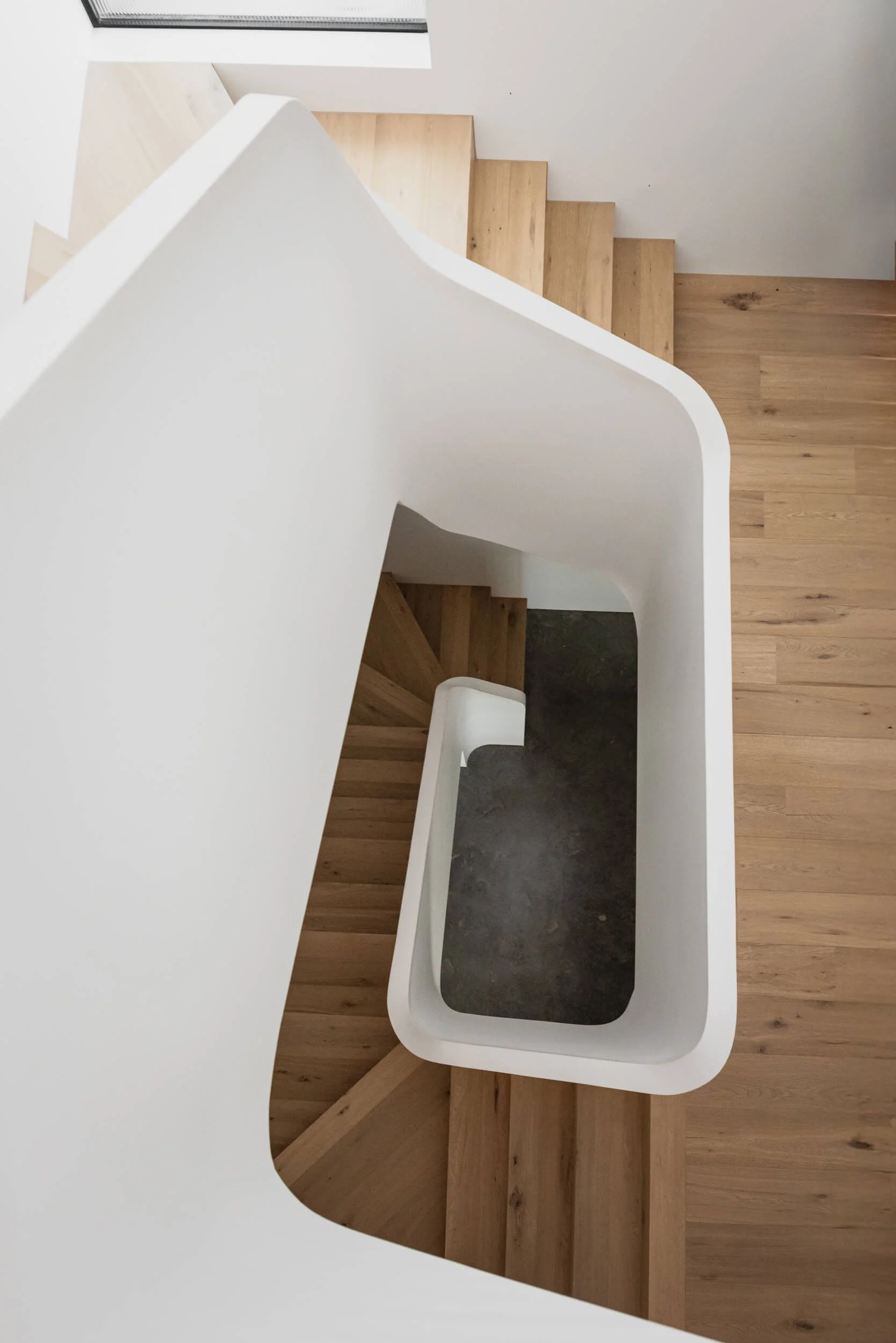 Top-down orthographic view of a white sculptural spiral staircase and smooth plaster walls at Stonemasons House. Architecture photography by Light & Lines