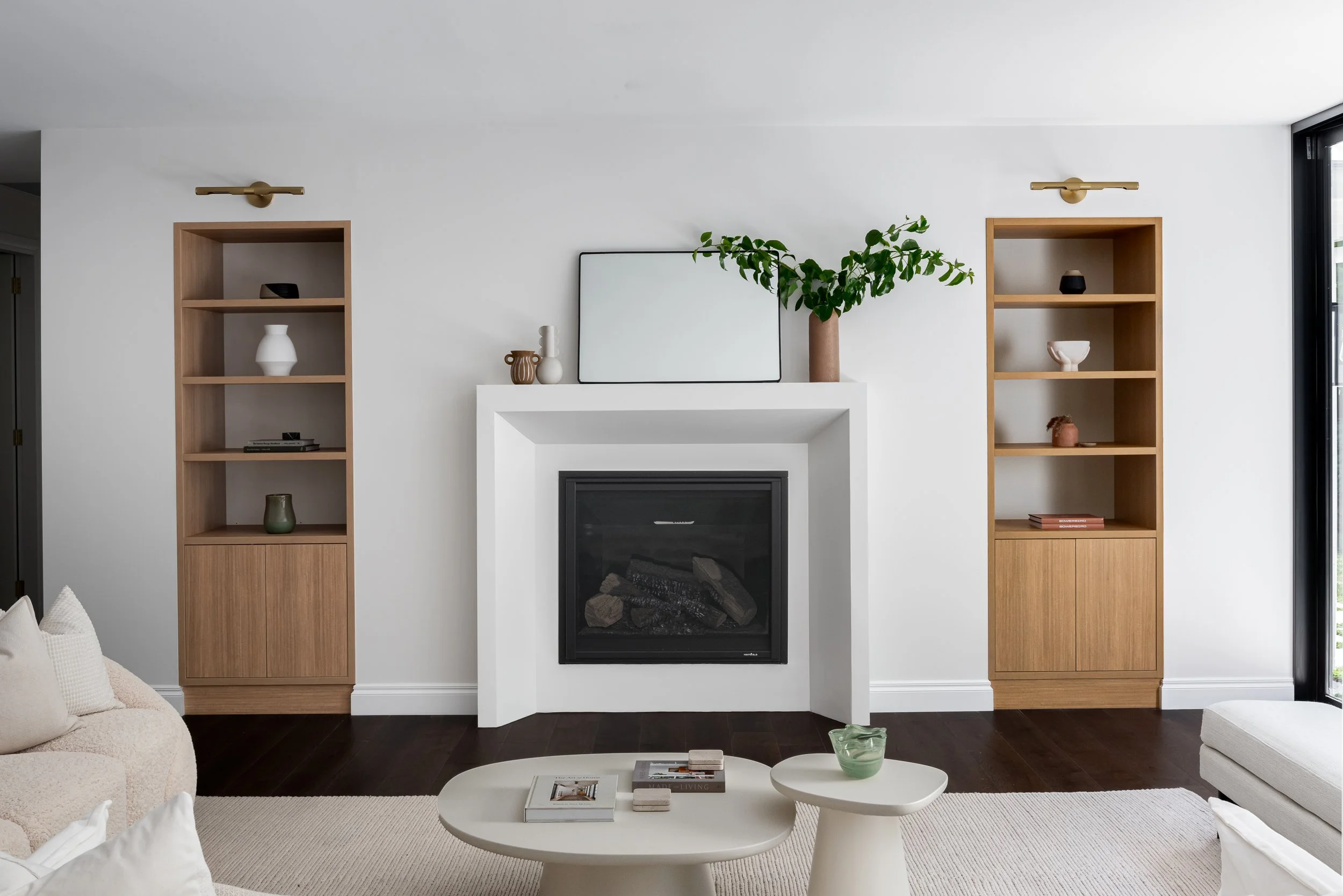 Feature white fireplace mantel flanked by custom oak bookcases and brass wall sconces built by Highlander Homes in Burradoo, Southern Highlands, NSW