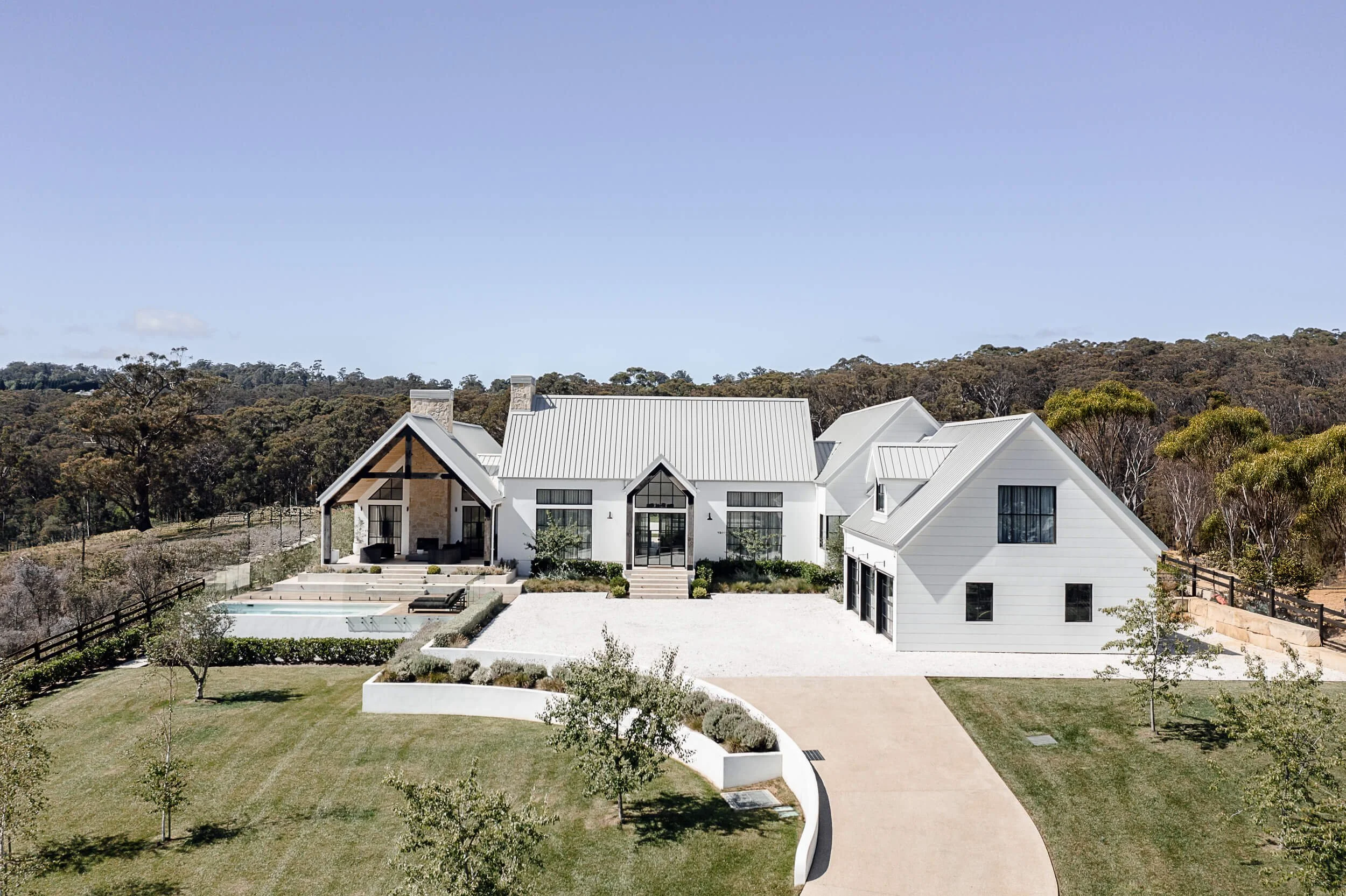 Architectural exterior photograph by Light & Lines of a contemporary luxury farmhouse with white siding and black trim, situated in the Southern Highlands, Regional New South Wales.