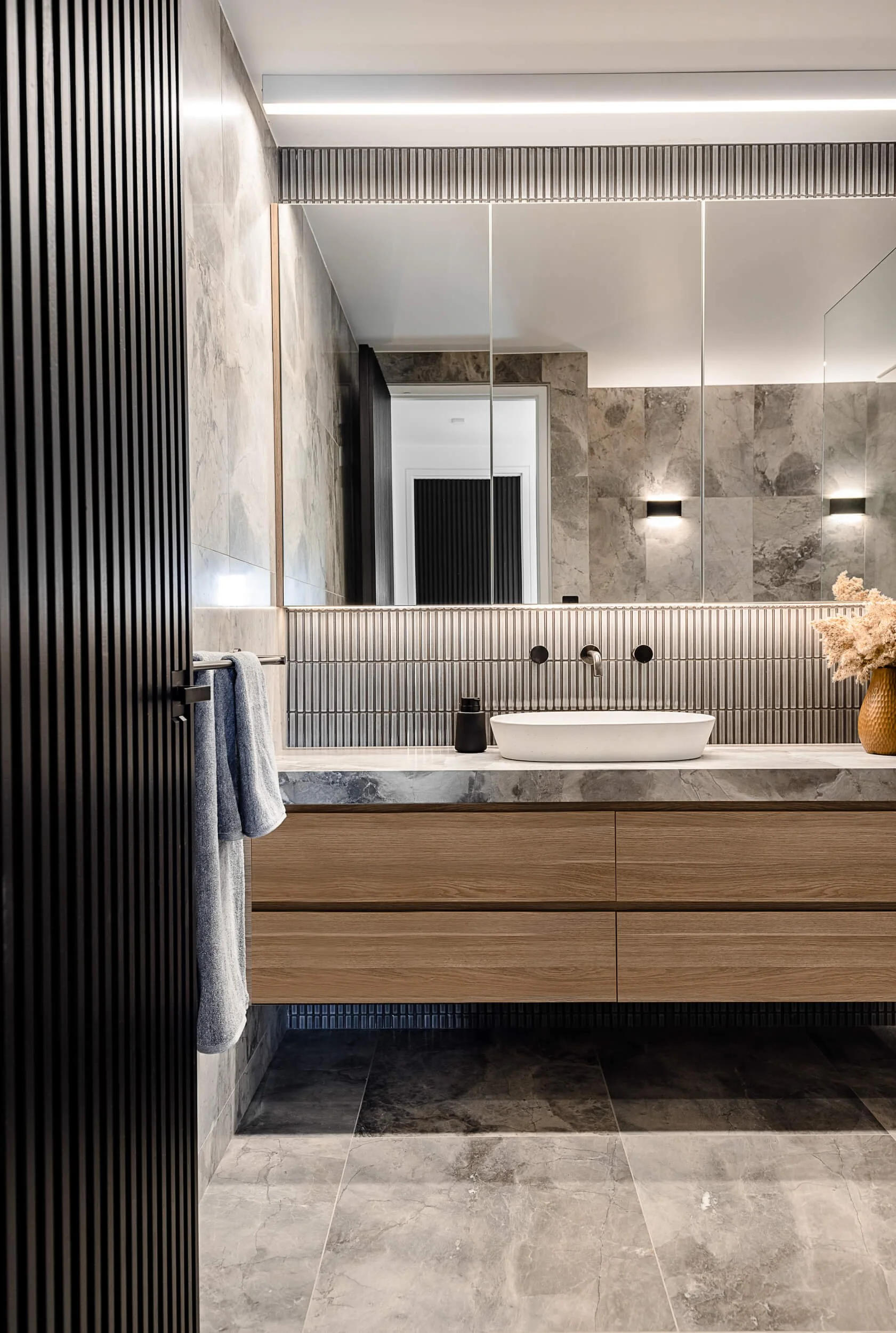 Premium architectural photography and film documenting true materiality and craftsmanship—highlighting seamless timber vanity drawers, ribbed feature tiles, and mirrored cabinetry—for Master Builders and designers in Regional NSW.