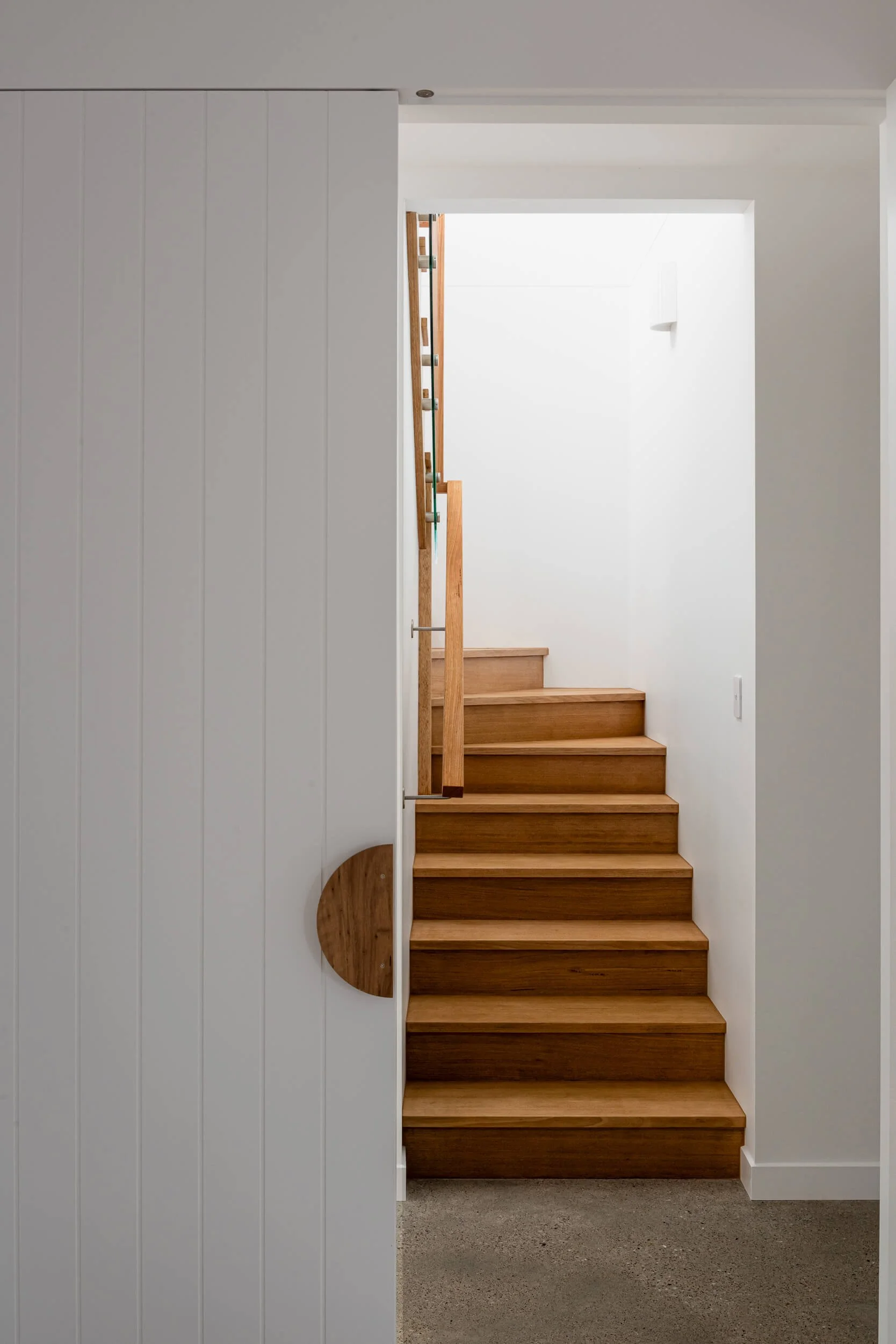 Timber staircase and custom paneled door with timber handle at Pacific 5. Premium architectural photography and film documenting true materiality and craftsmanship for Master Builders, architects and designers in Regional NSW.