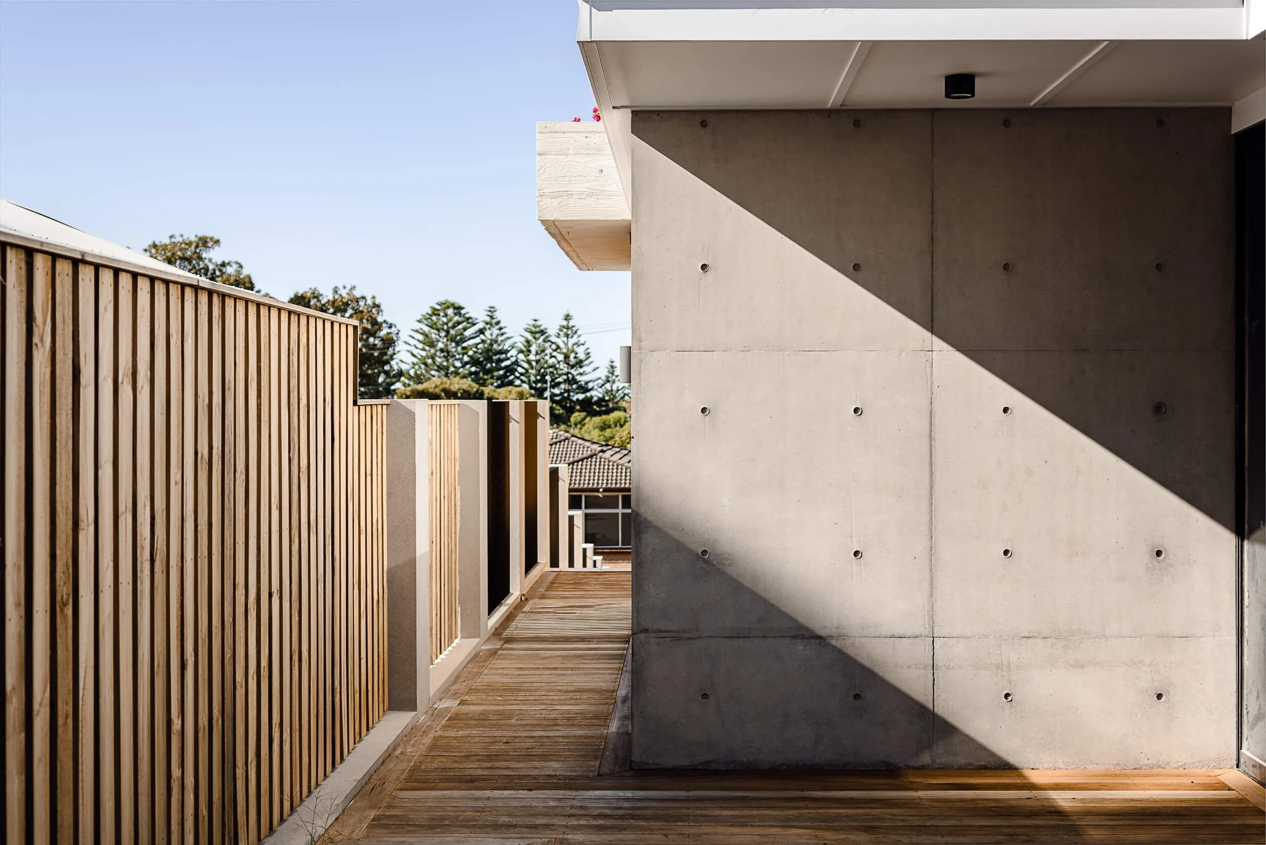 Premium architectural photography and film documenting true materiality and craftsmanship—highlighting raw off-form concrete facades, geometric shadow play, and vertical timber batten screening—for Master Builders and designers in Regional NSW.