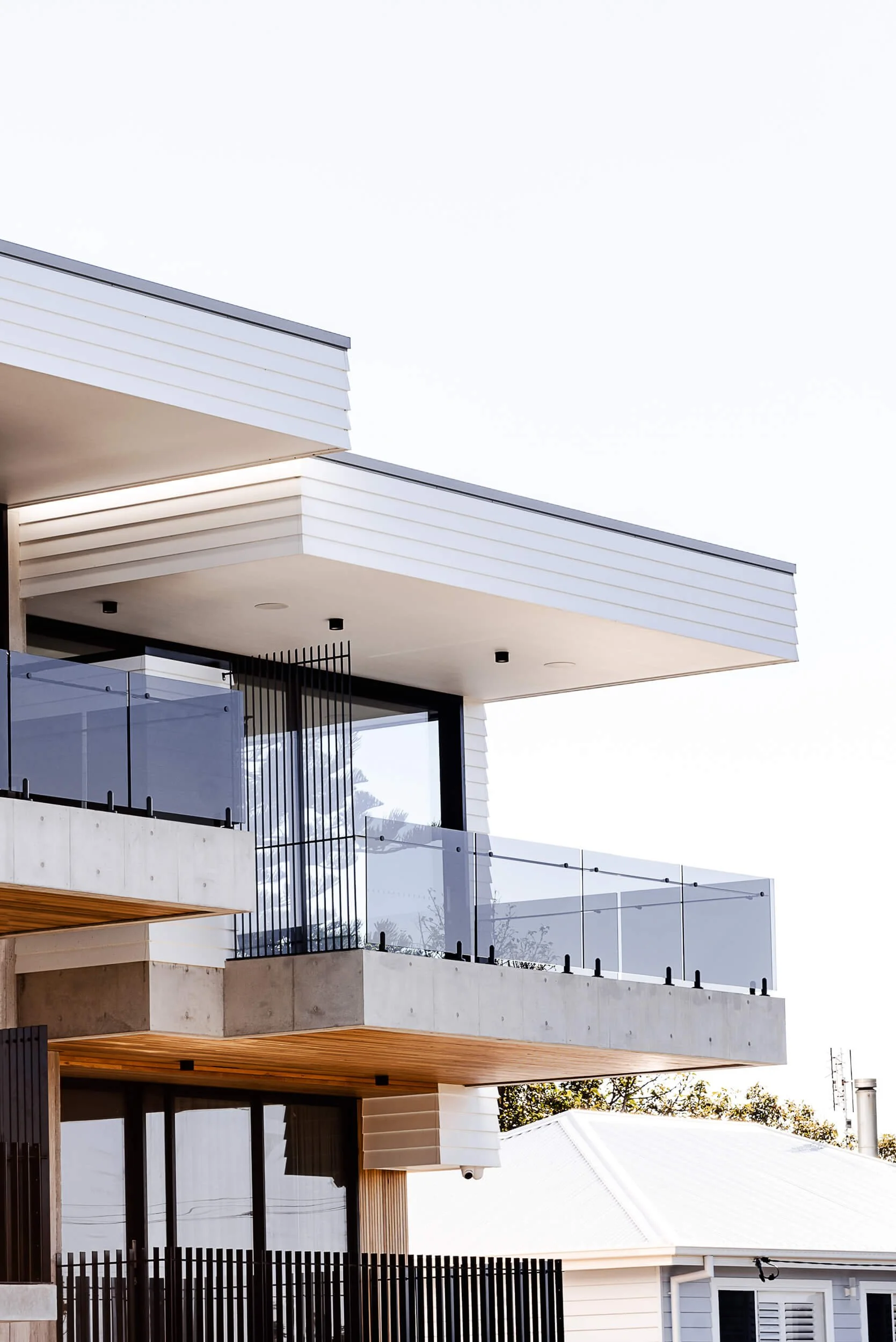Premium architectural photography and film documenting true materiality and craftsmanship—highlighting cantilevered concrete balconies, timber soffits, and modern linear cladding—for Master Builders and designers in Regional NSW.