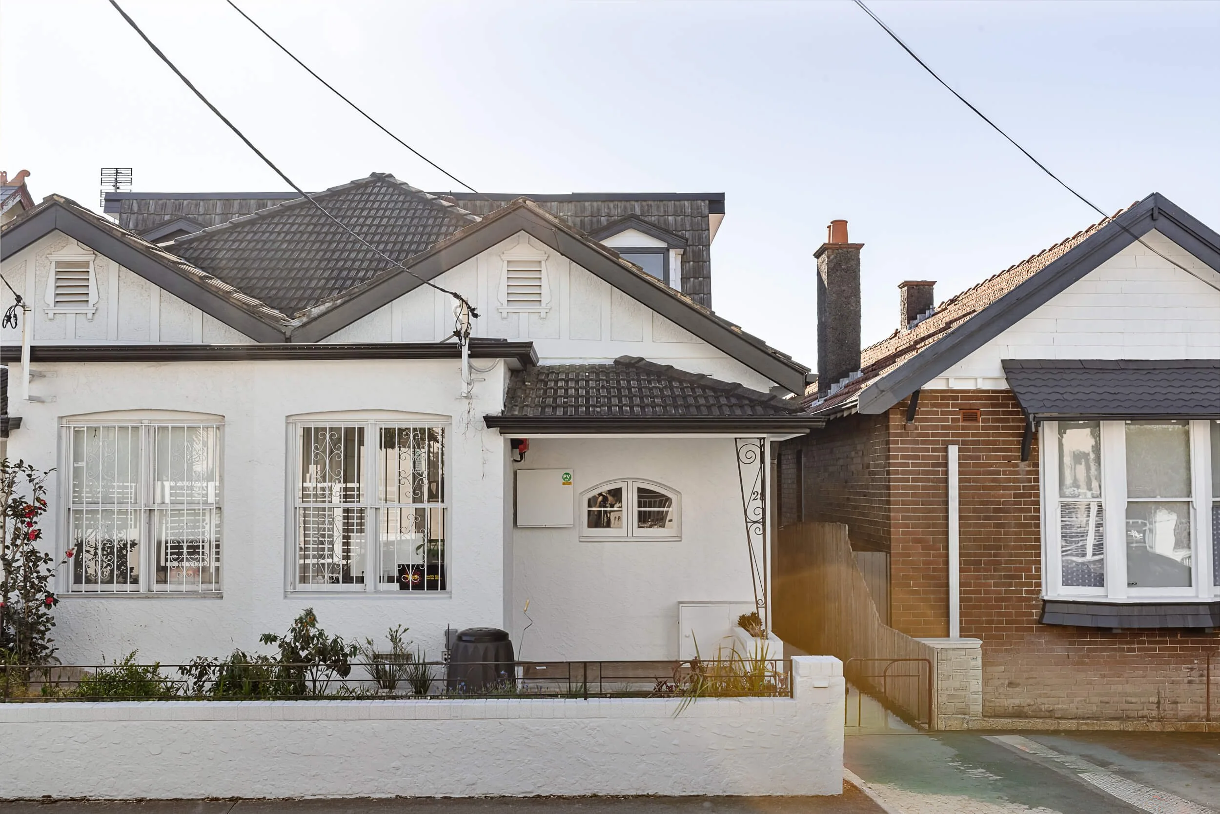 Exterior streetscape view of the restored white heritage semi-detached home facade with arched window details at Bondi Heights in Sydney, NSW