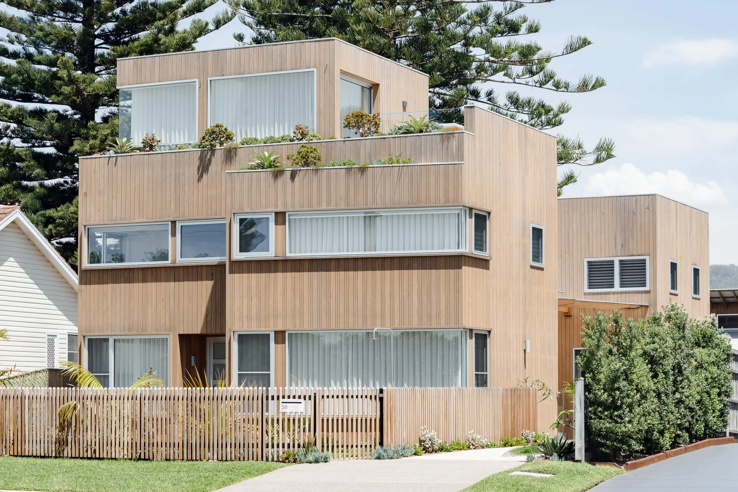 Timber-clad facade and rooftop gardens of Pacific 5 at Werri Beach. Premium architectural photography and film documenting true materiality, spatial flow, and craftsmanship for Master Builders and designers in Regional NSW.
