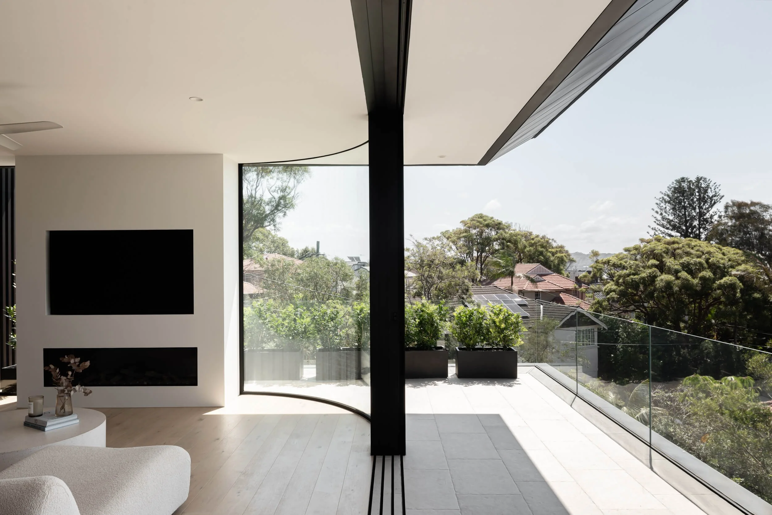 Curved panoramic window framing harbour views in living room at Stonemasons House. Architecture photography by Light & Lines