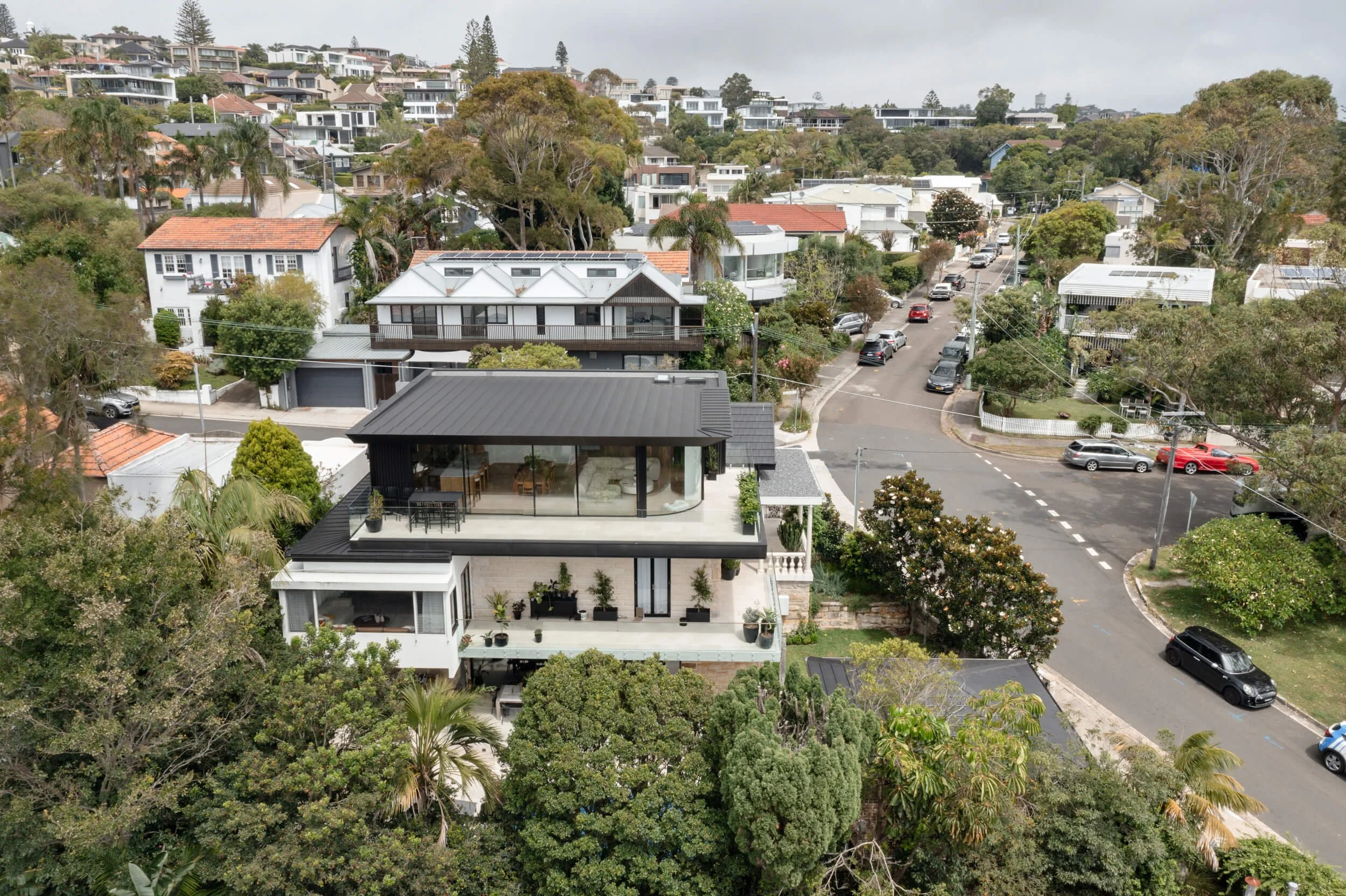 High-angle aerial capture of cantilevered balcony and curved glass at Stonemasons House