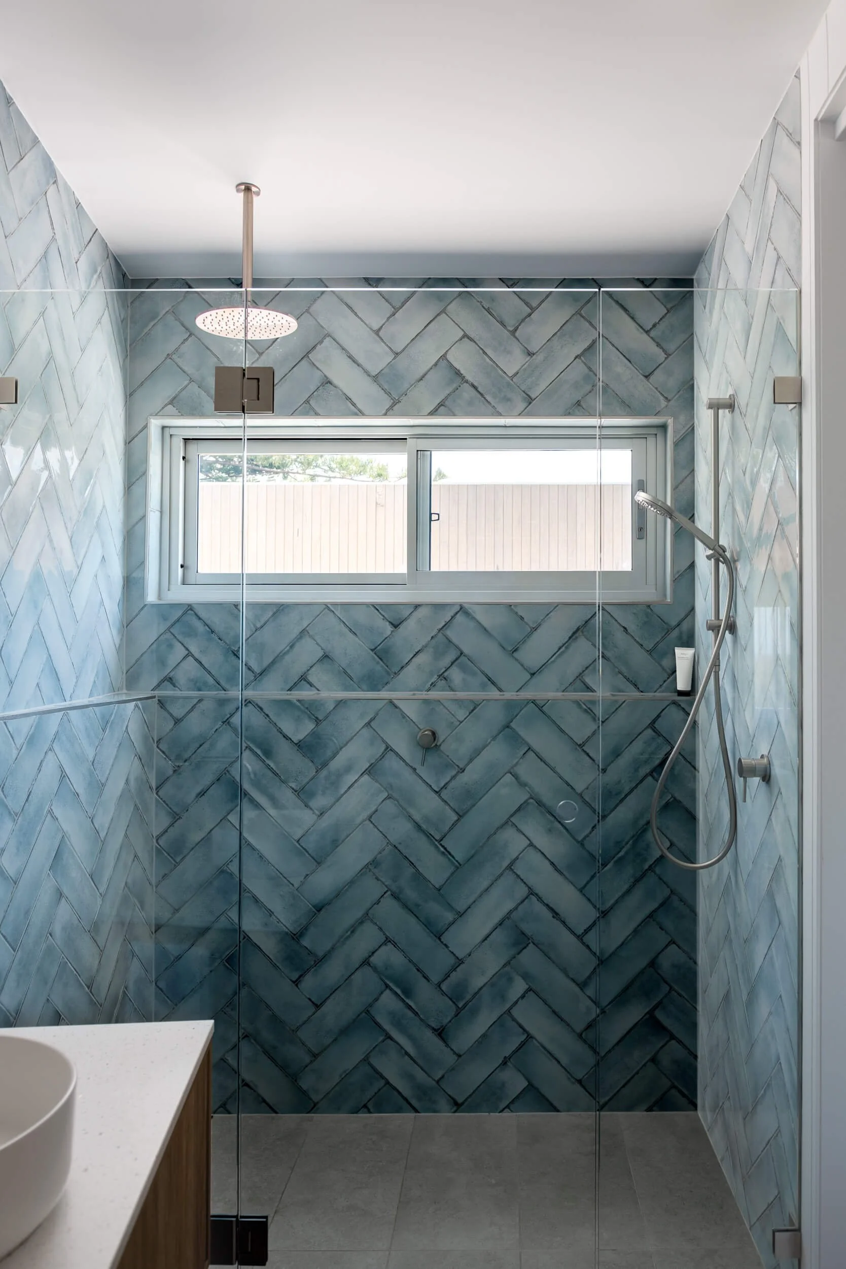 bathroom shower featuring blue herringbone tiles and frameless glass at Pacific 5. Premium architectural photography and film documenting true materiality and craftsmanship for Master Builders, architects and designers in Regional NSW.