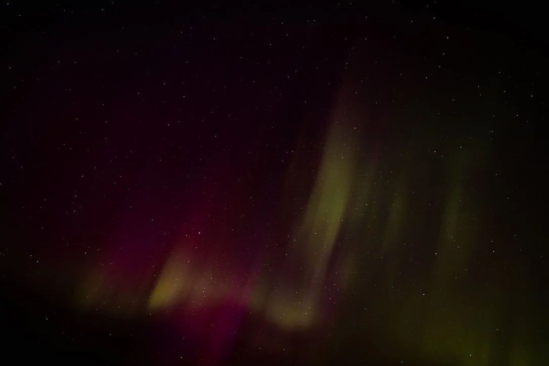 Night sky illuminated by colorful aurora borealis with visible stars.