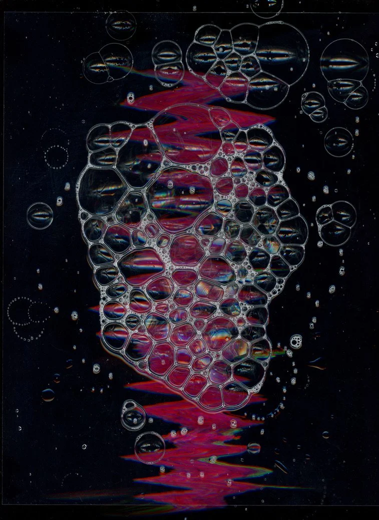 Close-up of soap bubbles forming an abstract pattern against a dark background. Created with scanography