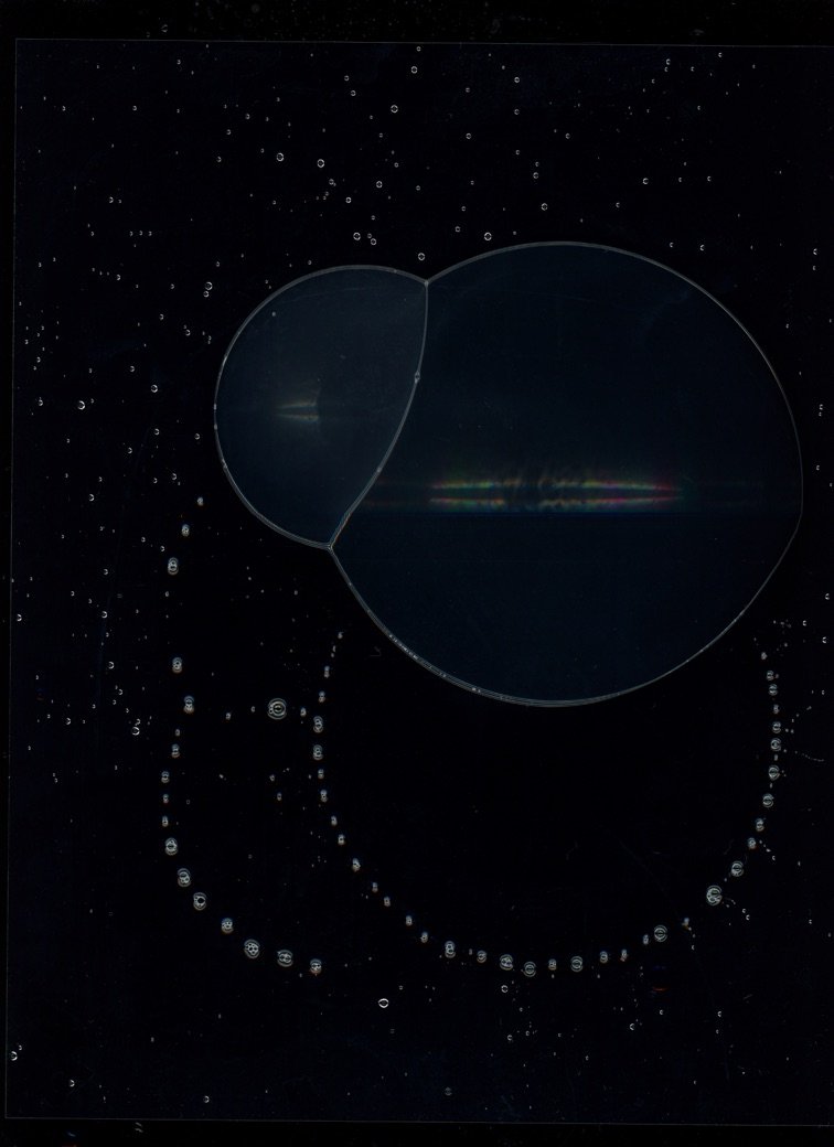 Close-up of a bubble in water with smaller bubbles surrounding it, against a black background. Created with scanography