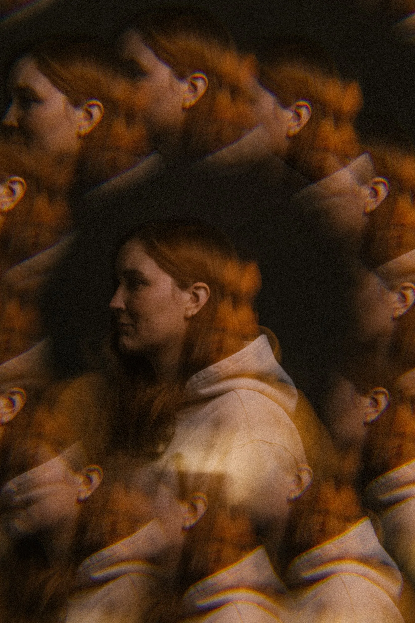 Multiple overlapping images of a woman with red hair in a white hoodie, creating a layered, kaleidoscopic visual effect.
