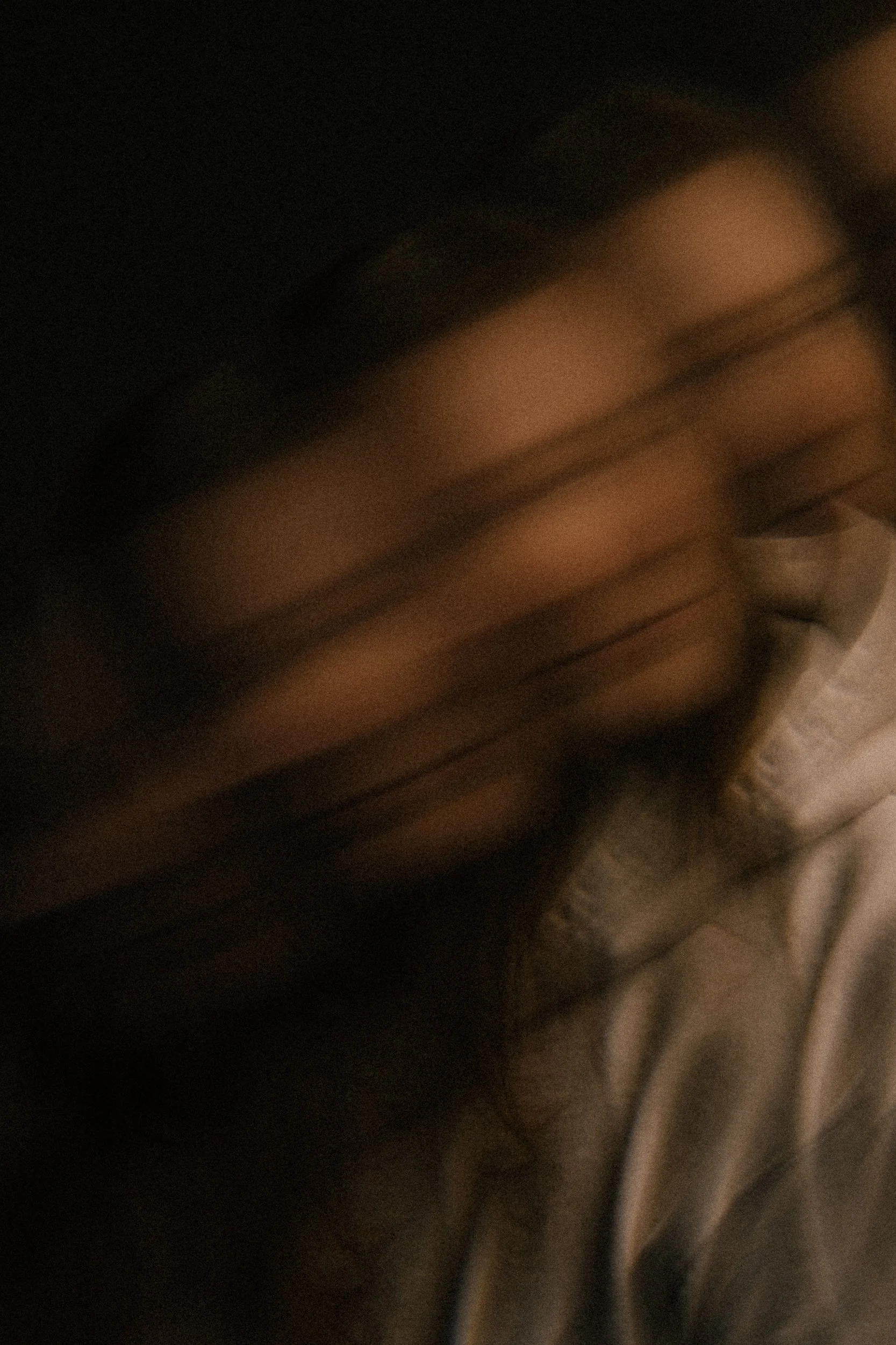 A blurred close-up of a person with long dark hair, appearing to be in motion or in low light.