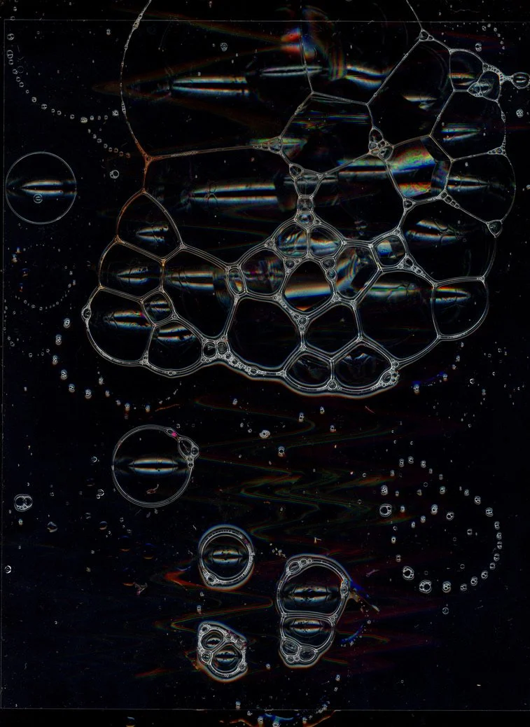 Close-up of soap bubbles with iridescent colors floating in dark space. Created with scanography
