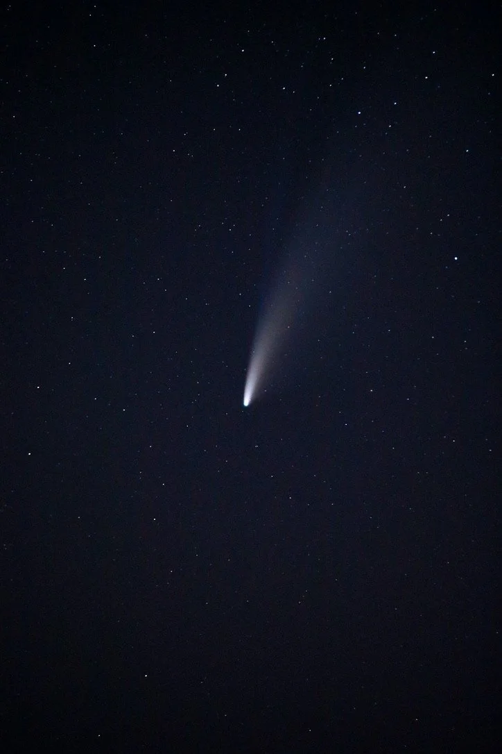Night sky with a bright comet and numerous stars scattered across the sky.